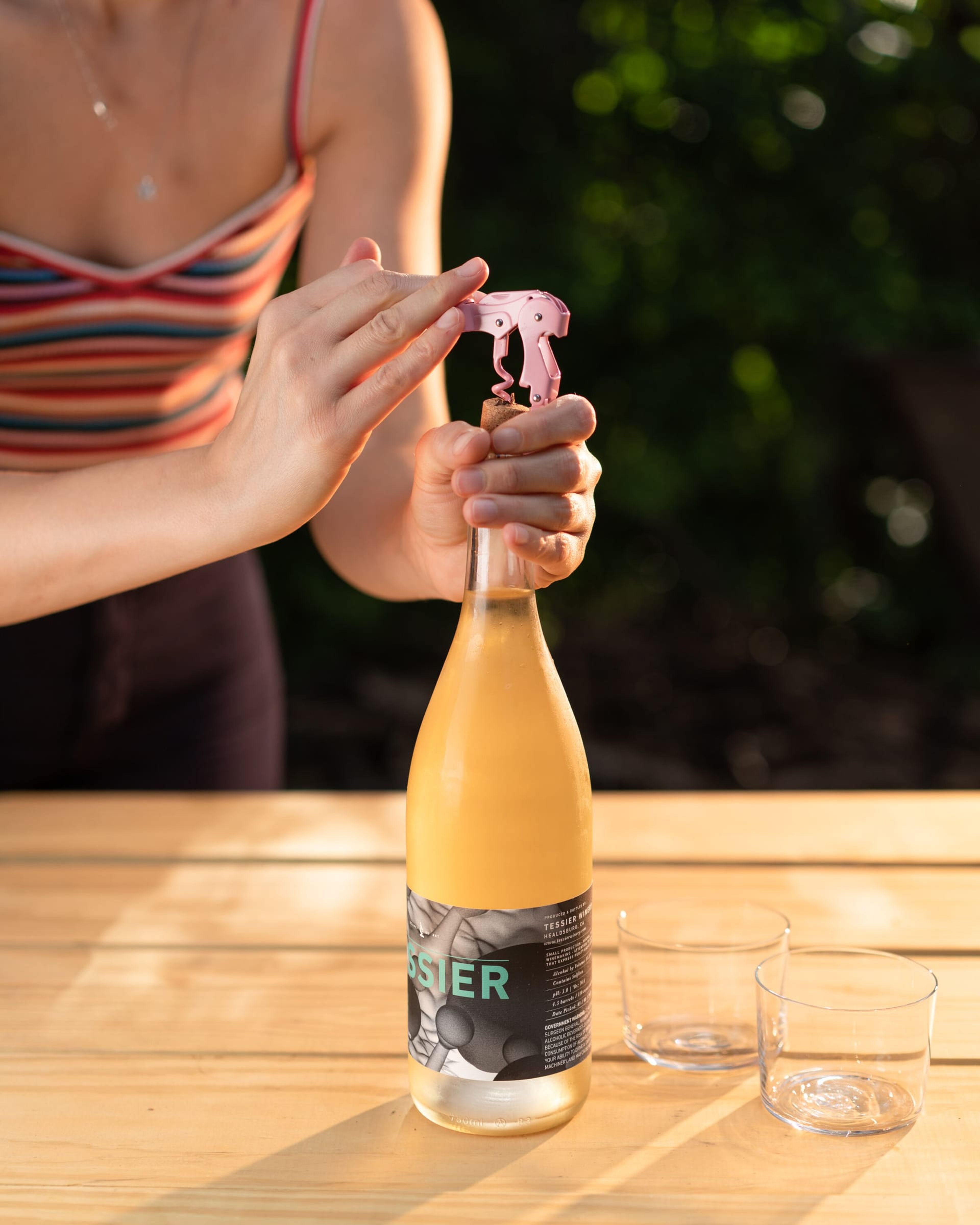 Opening a bottle of pét-nat on a sunlit table