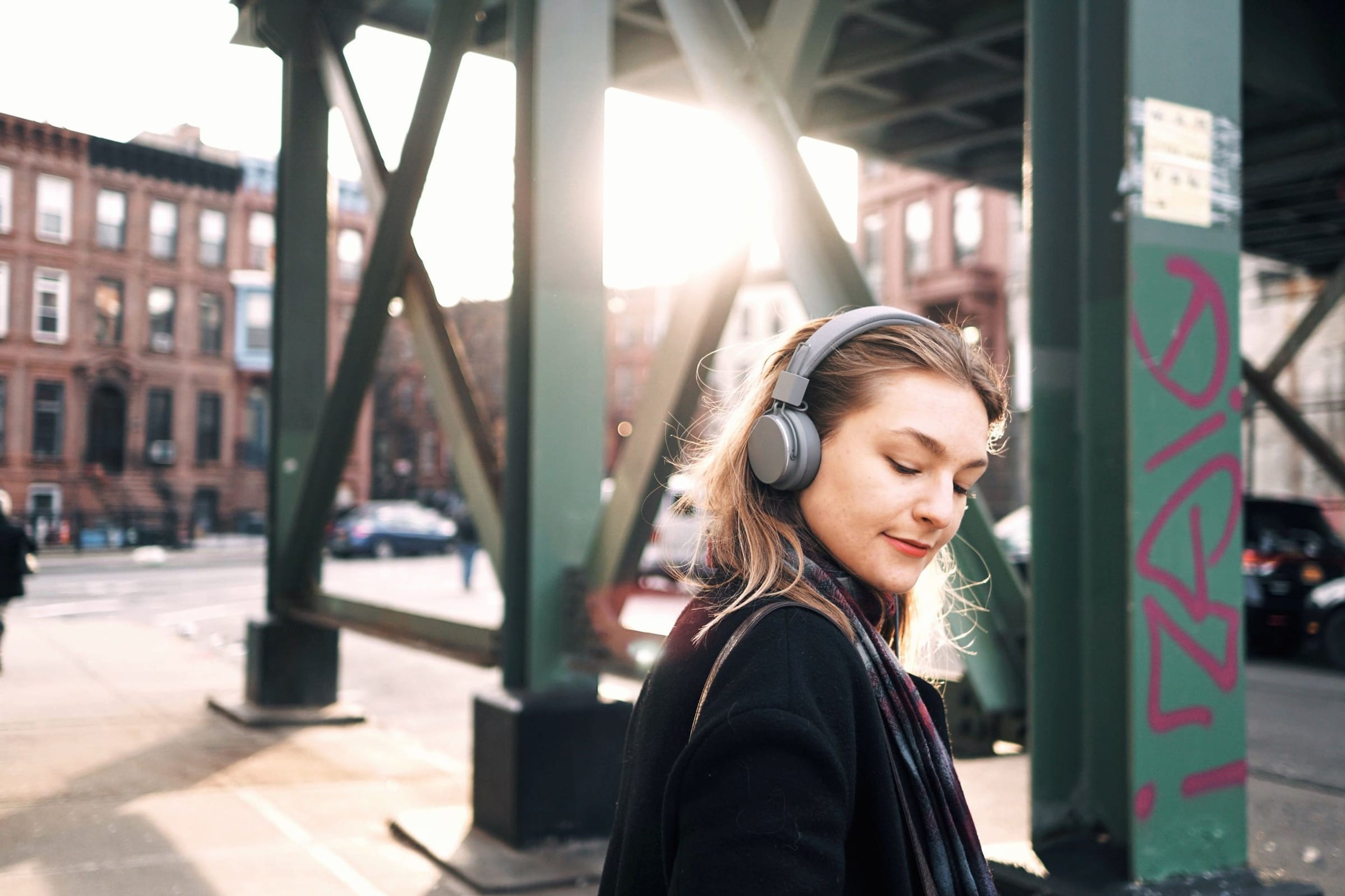 Urbanears: woman wearing Urbanears headphones under an elevated train