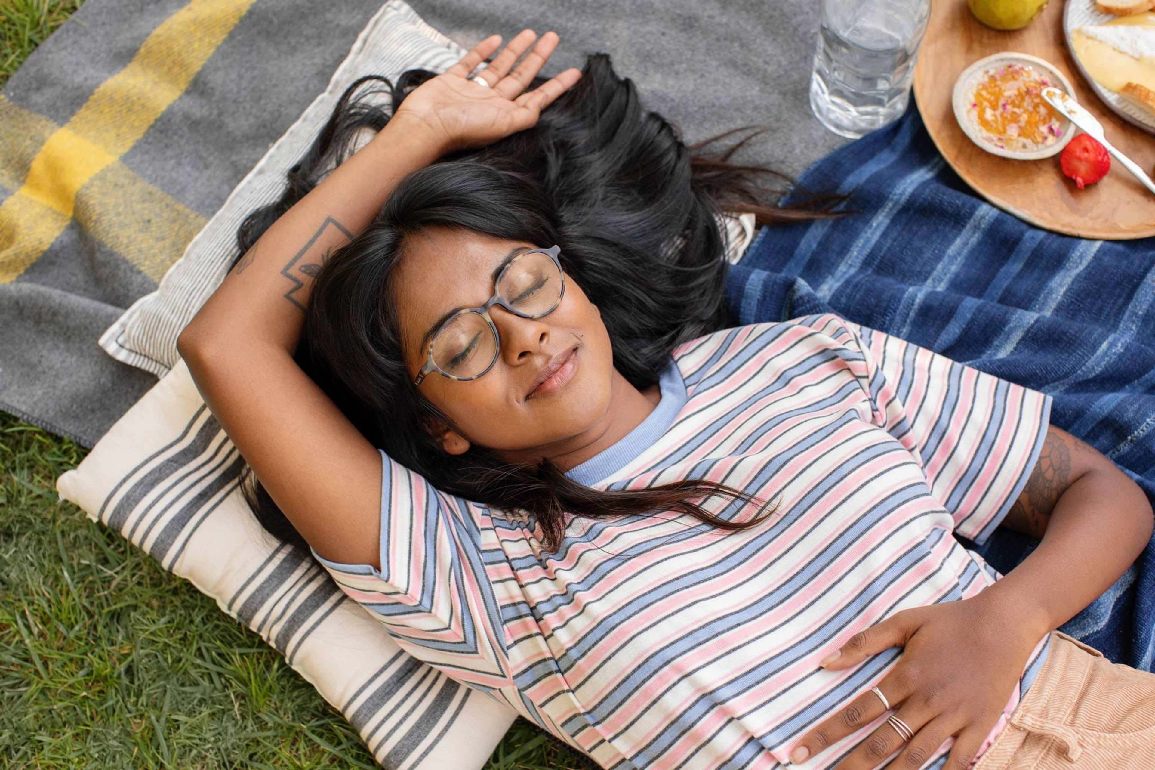 Woman lying on a picnic blanket with her eyes closed
