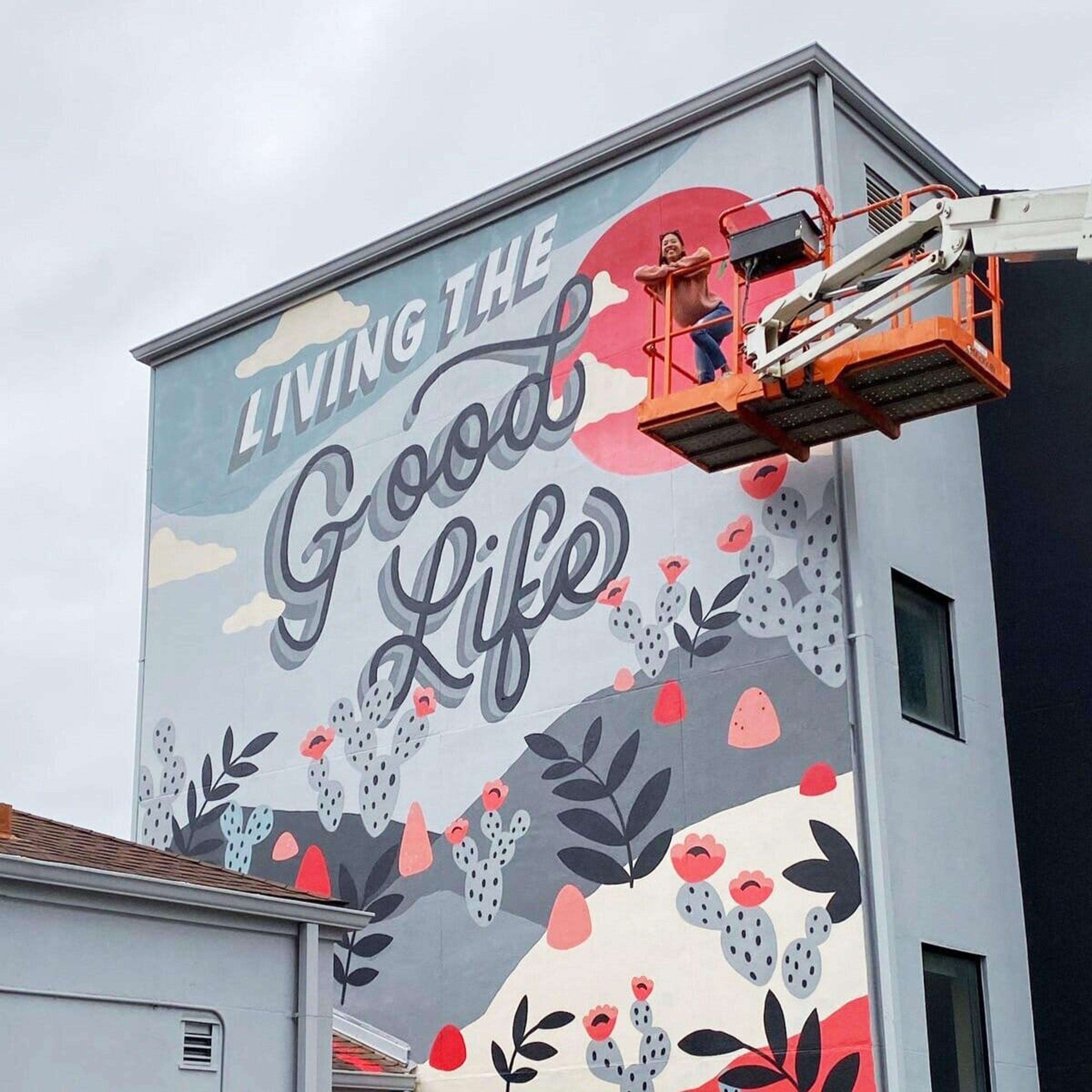 “Living the Good Life” mural being painted from a lift
