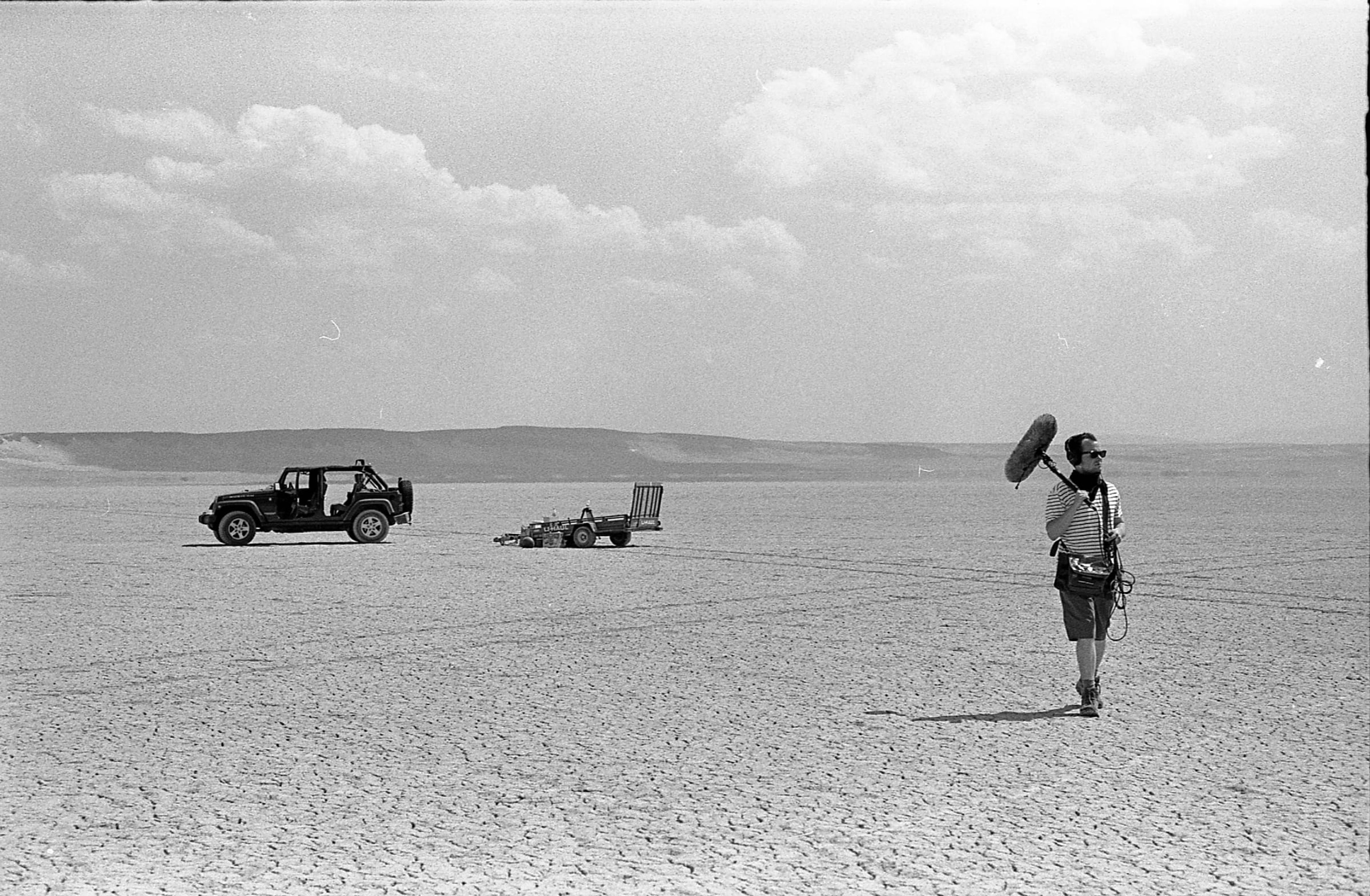 Boom operator on a desert lakebed with a jeep in the distance