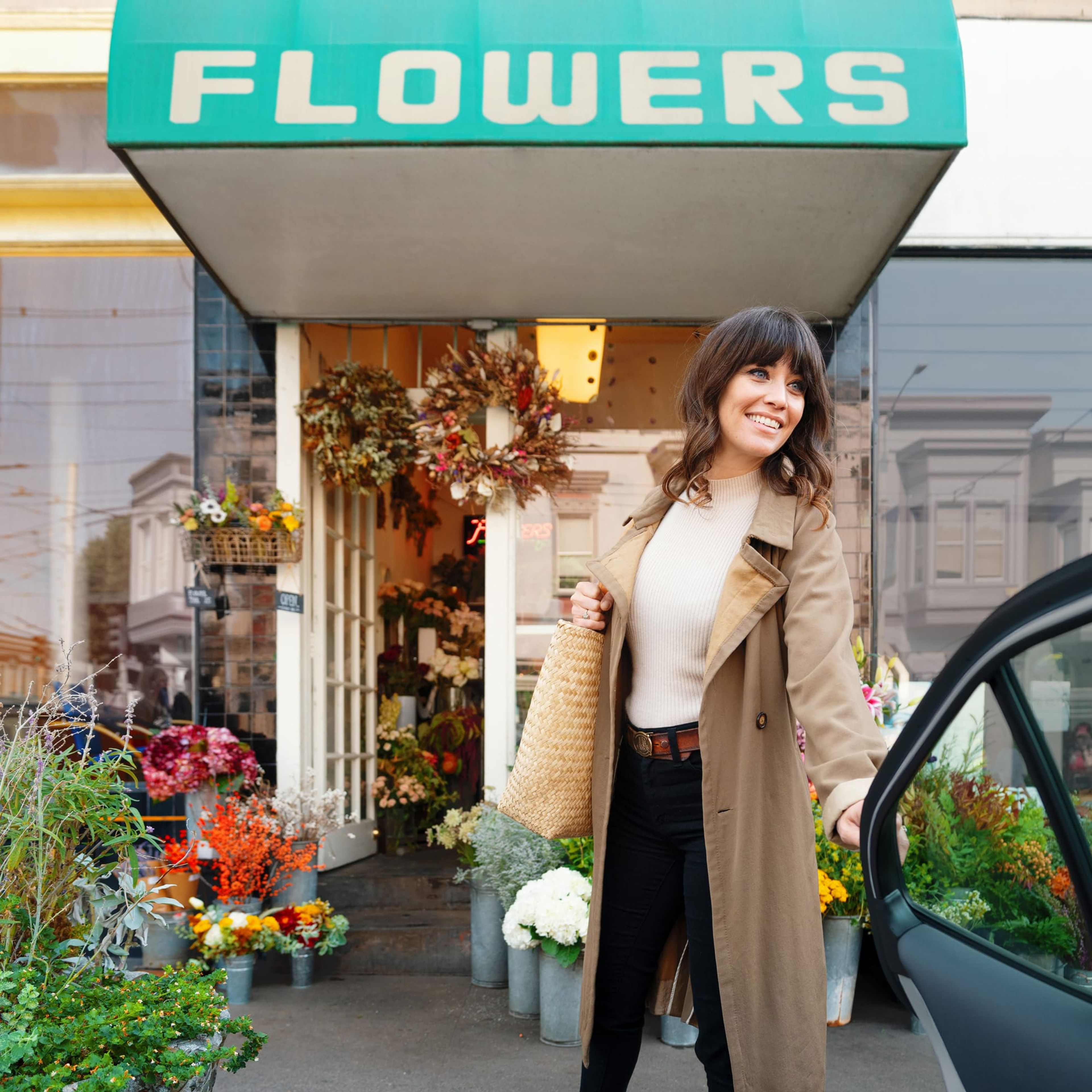 Woman stepping out of a car in front of a flower shop