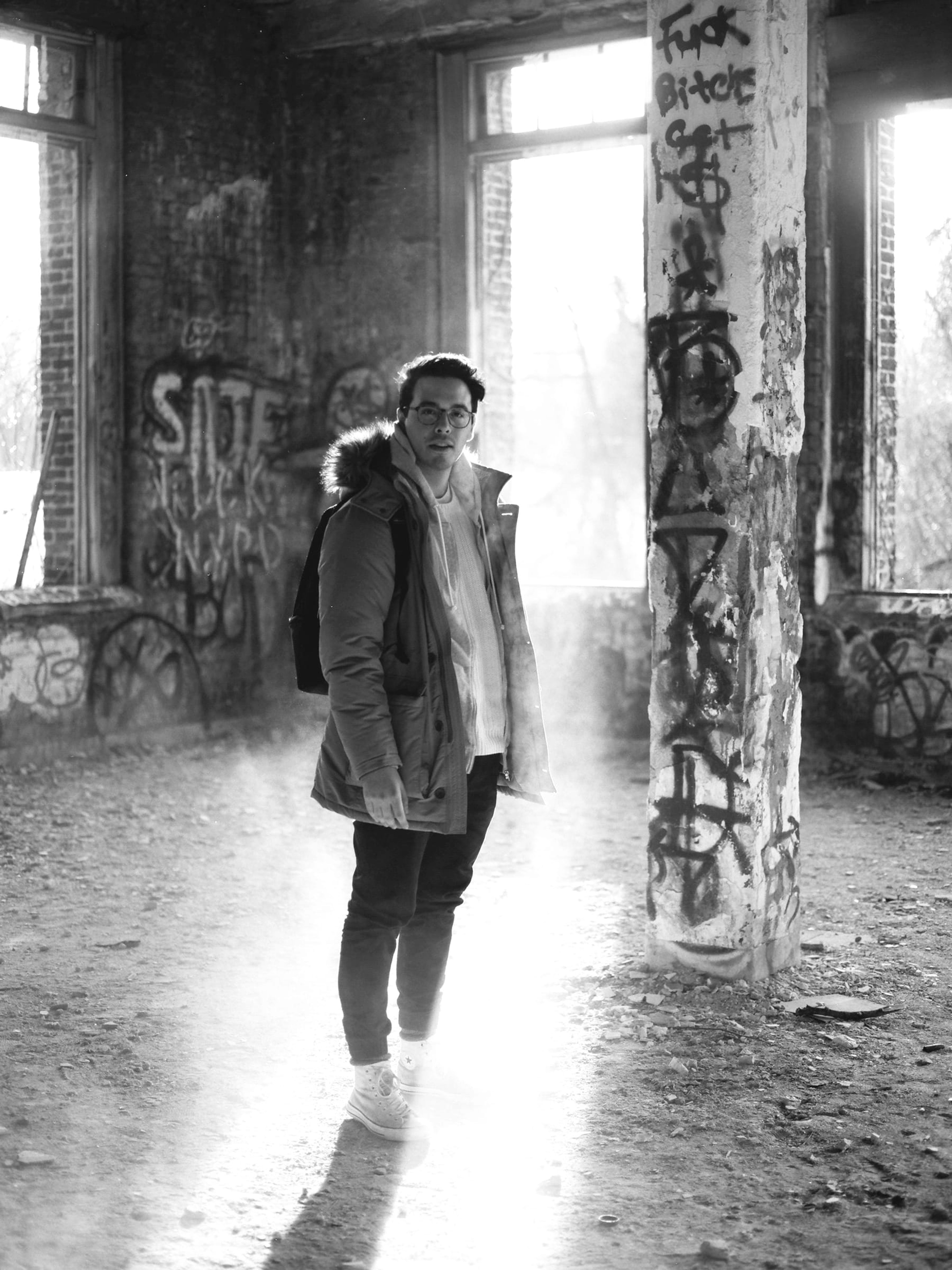 Black-and-white portrait of Sean in an abandoned, graffitied building