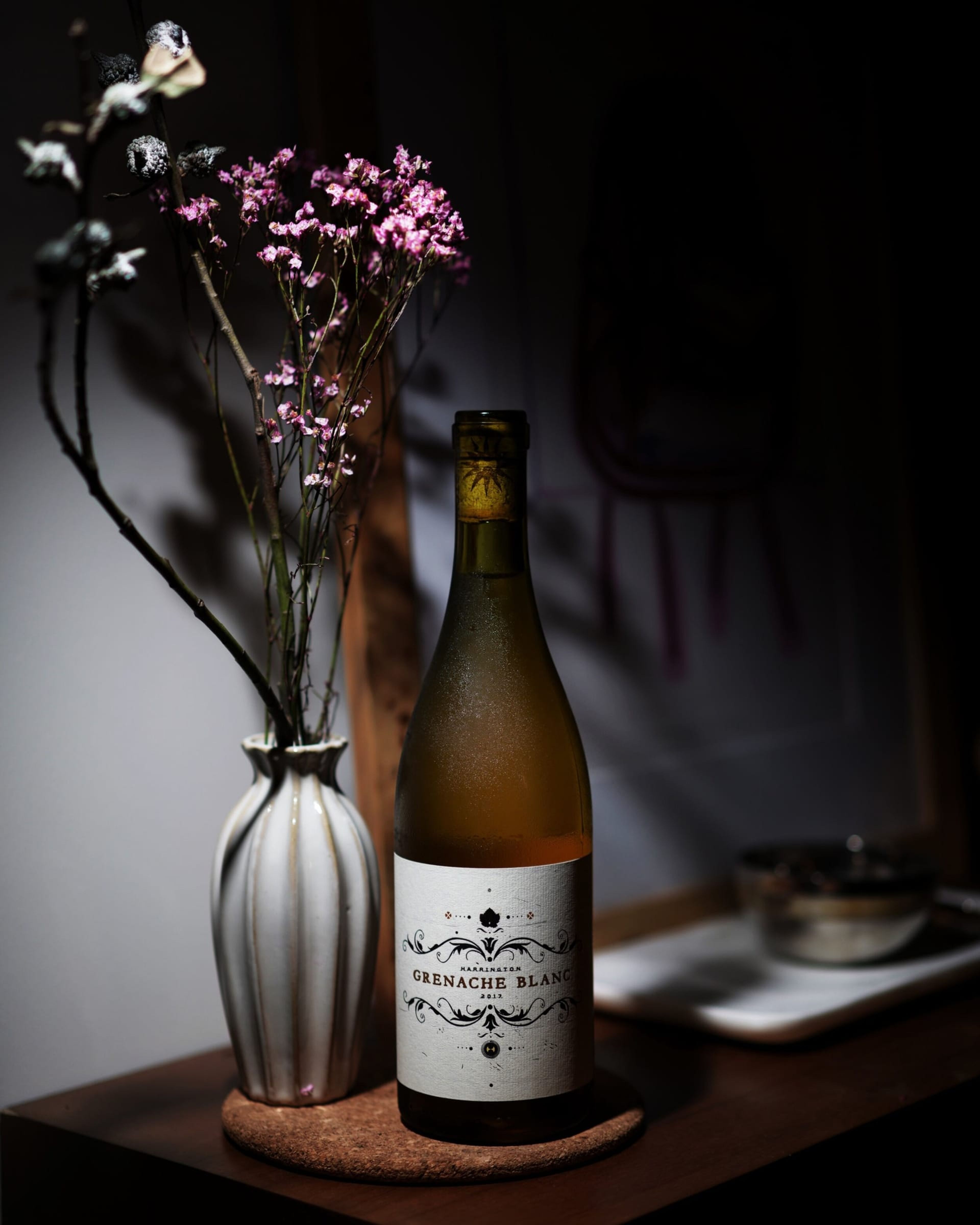 Bottle of Grenache Blanc beside a vase of dried flowers
