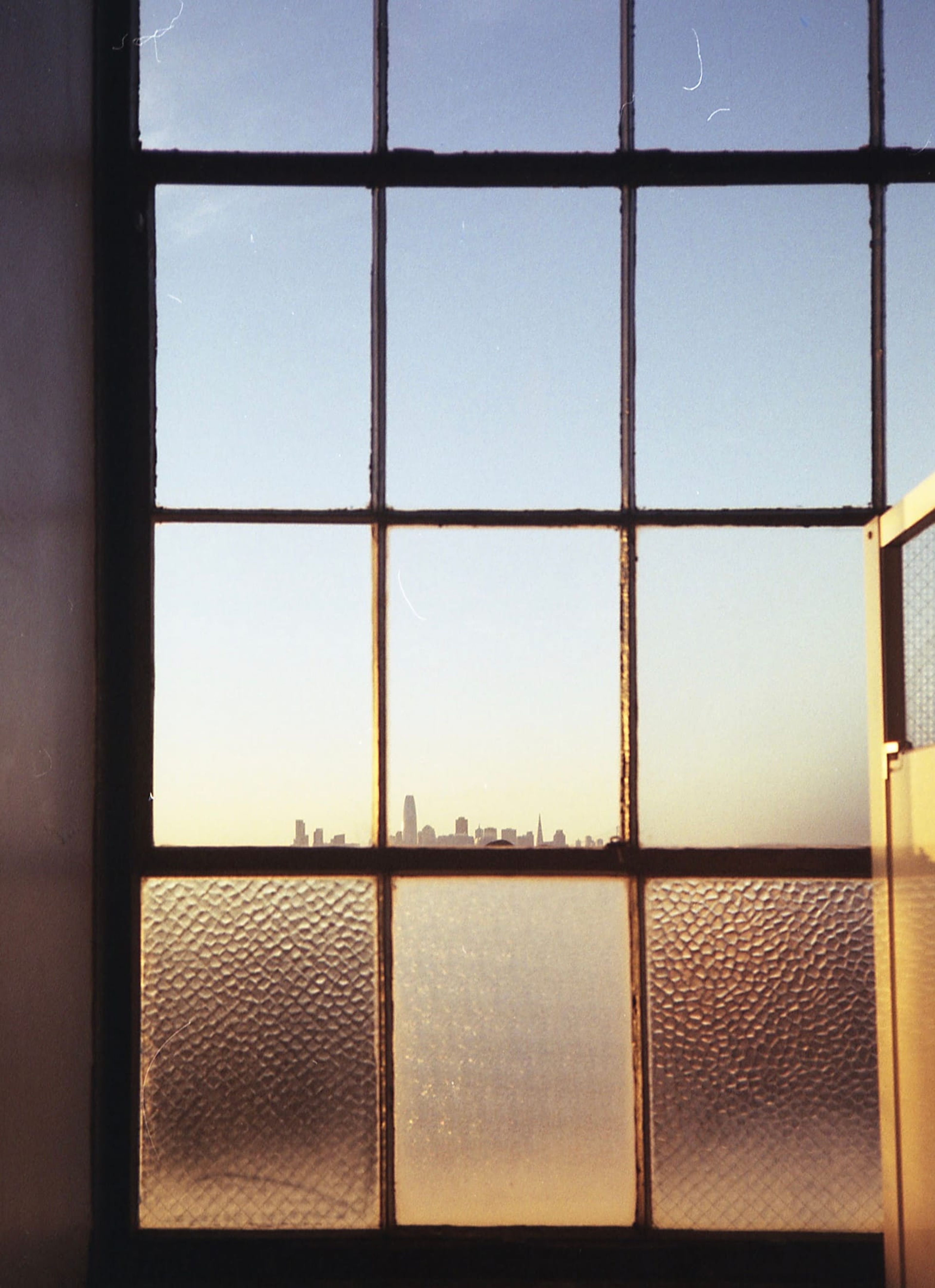 City skyline through an old paned window at sunset