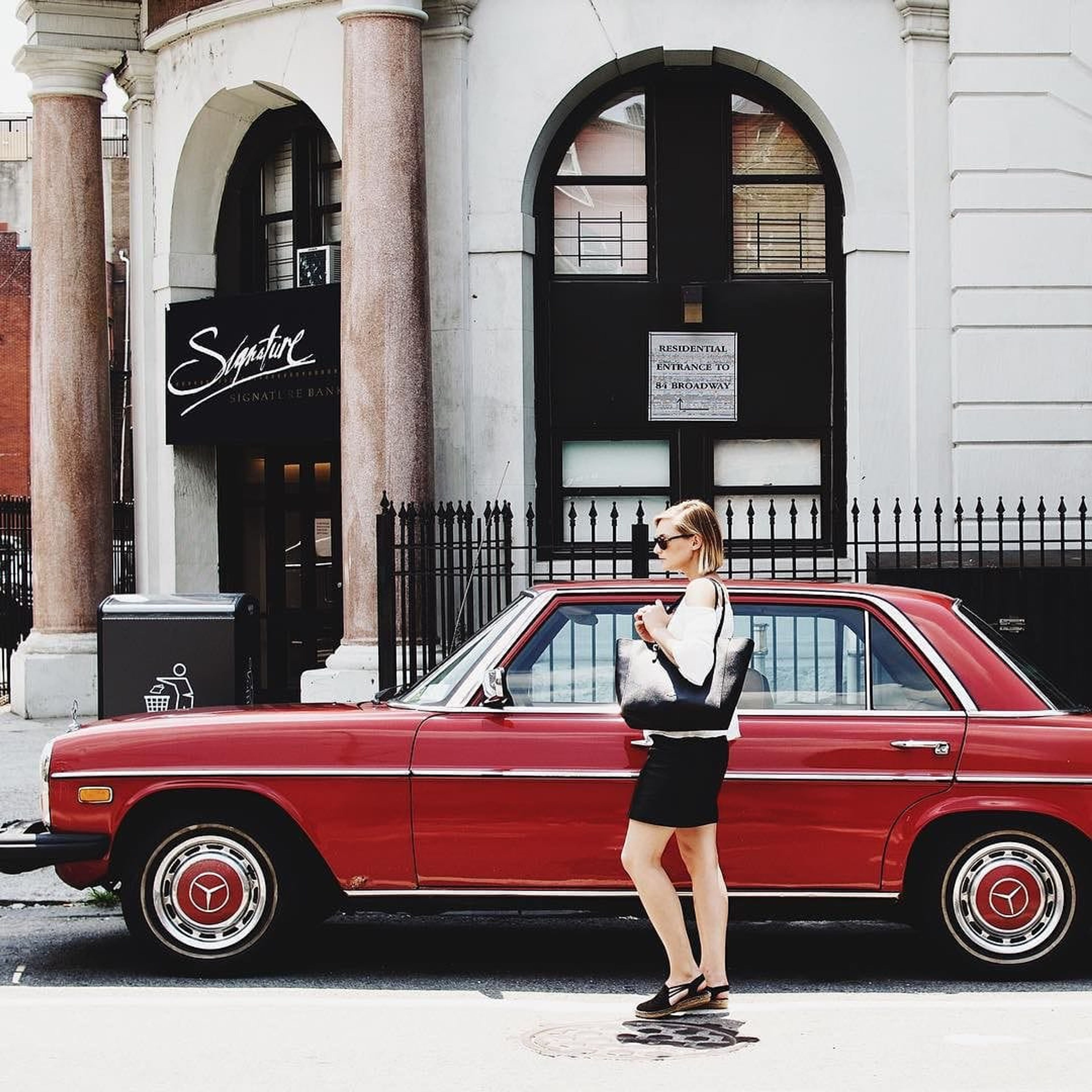 Coach: woman with a Coach bag walking past a red vintage Mercedes