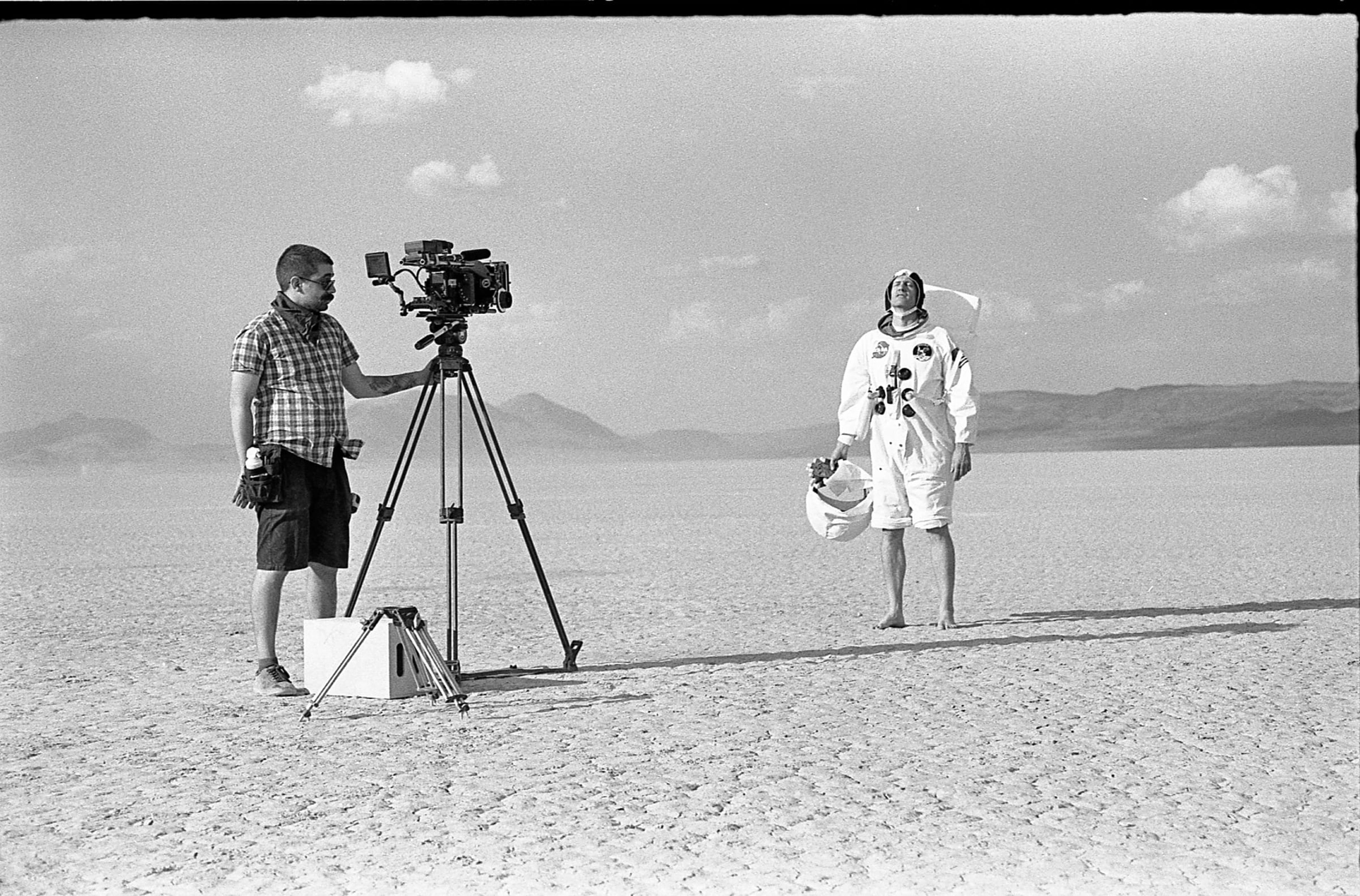 Camera operator and an actor in a spacesuit on a desert lakebed