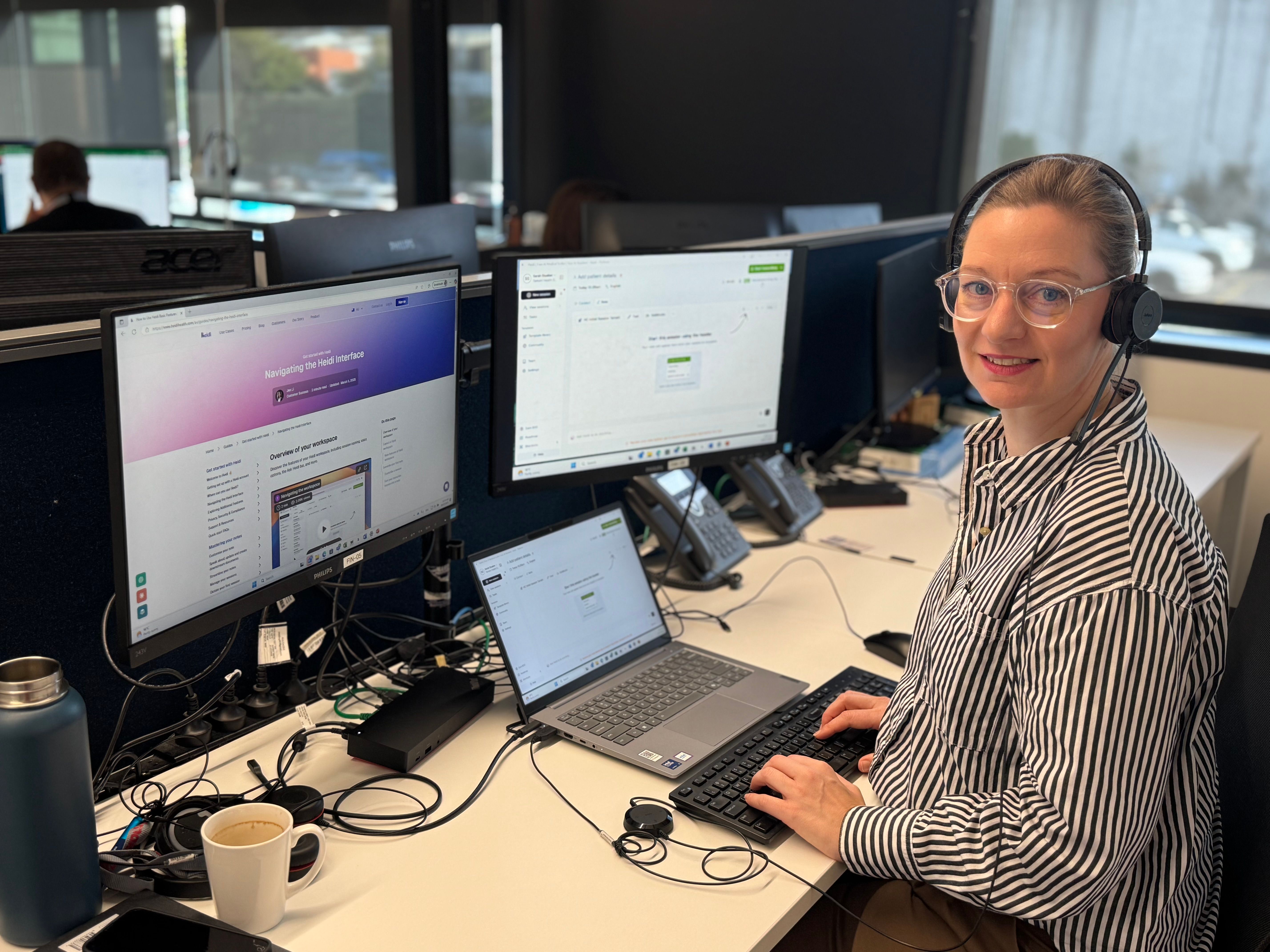 a woman wearing headphones is sitting at a desk in front of a computer .