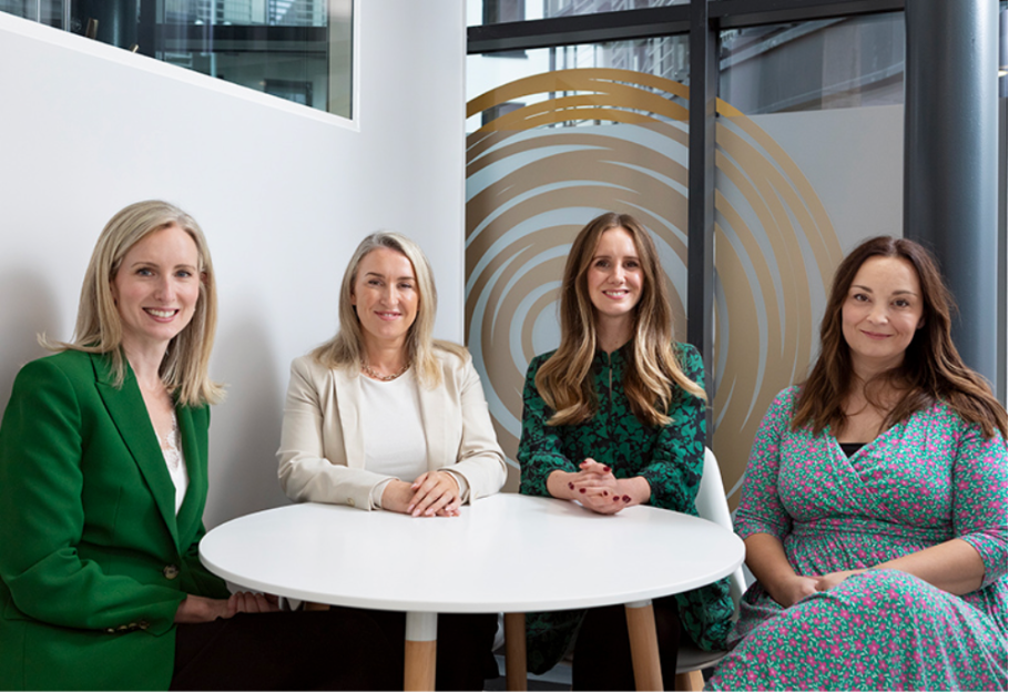 Four smiling women seated at a table.