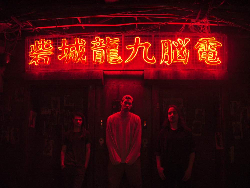 Markus, Sven and Daniel posing below a Neon sign with Chinese characters. The scene is tinted red from the neon sign.