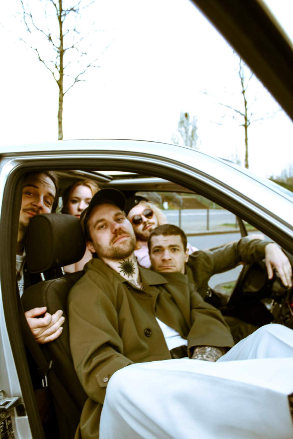 Whole band sitting in a car, window open