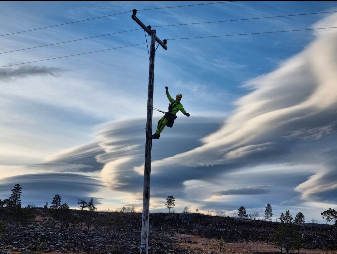 Montør i stolpe med vakker himmel i bakgrunnen.