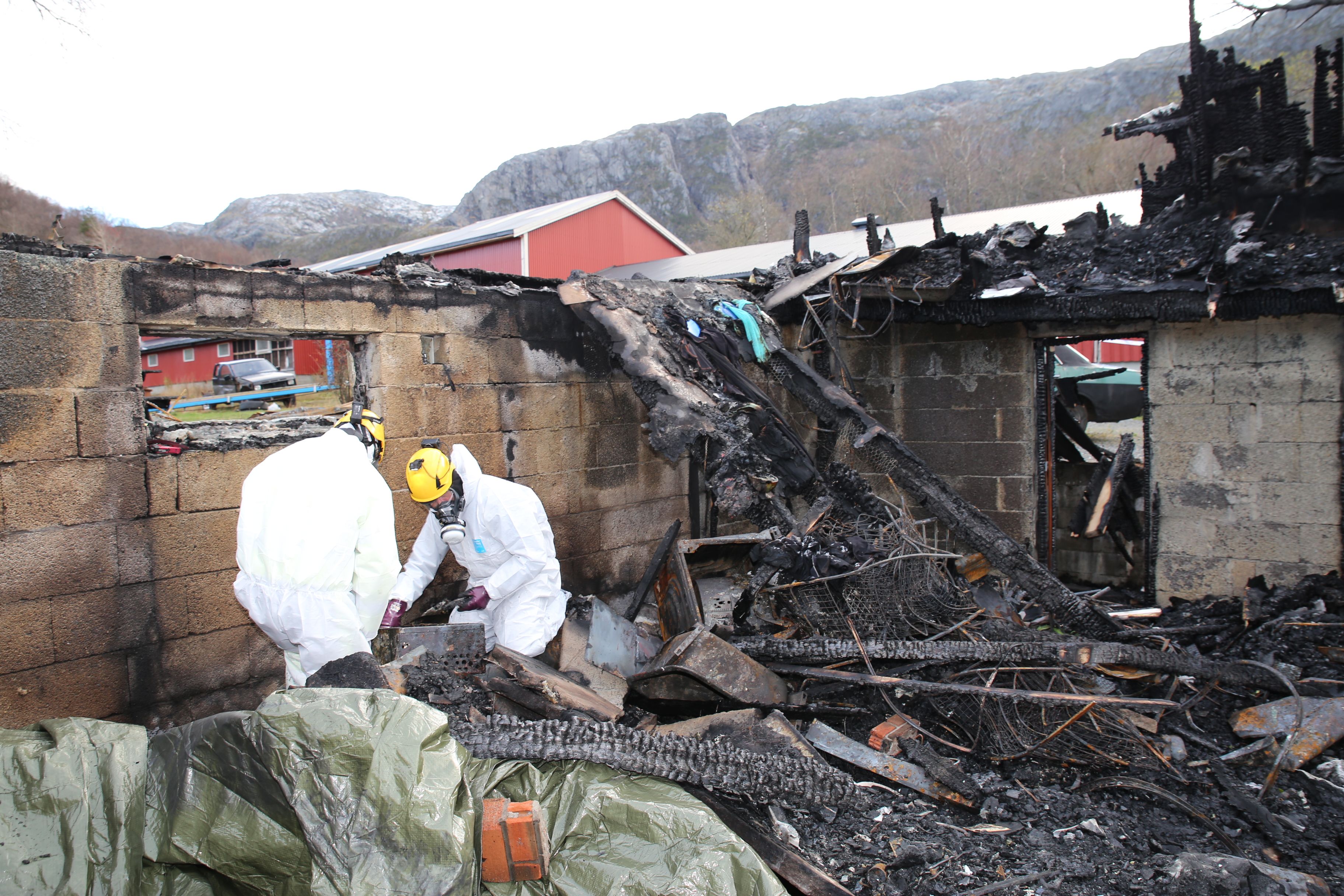 To arbeidere etterforsker brann i bygning som nesten er brent ned.