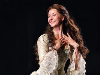 Leonie performing as Christine in a white dress.