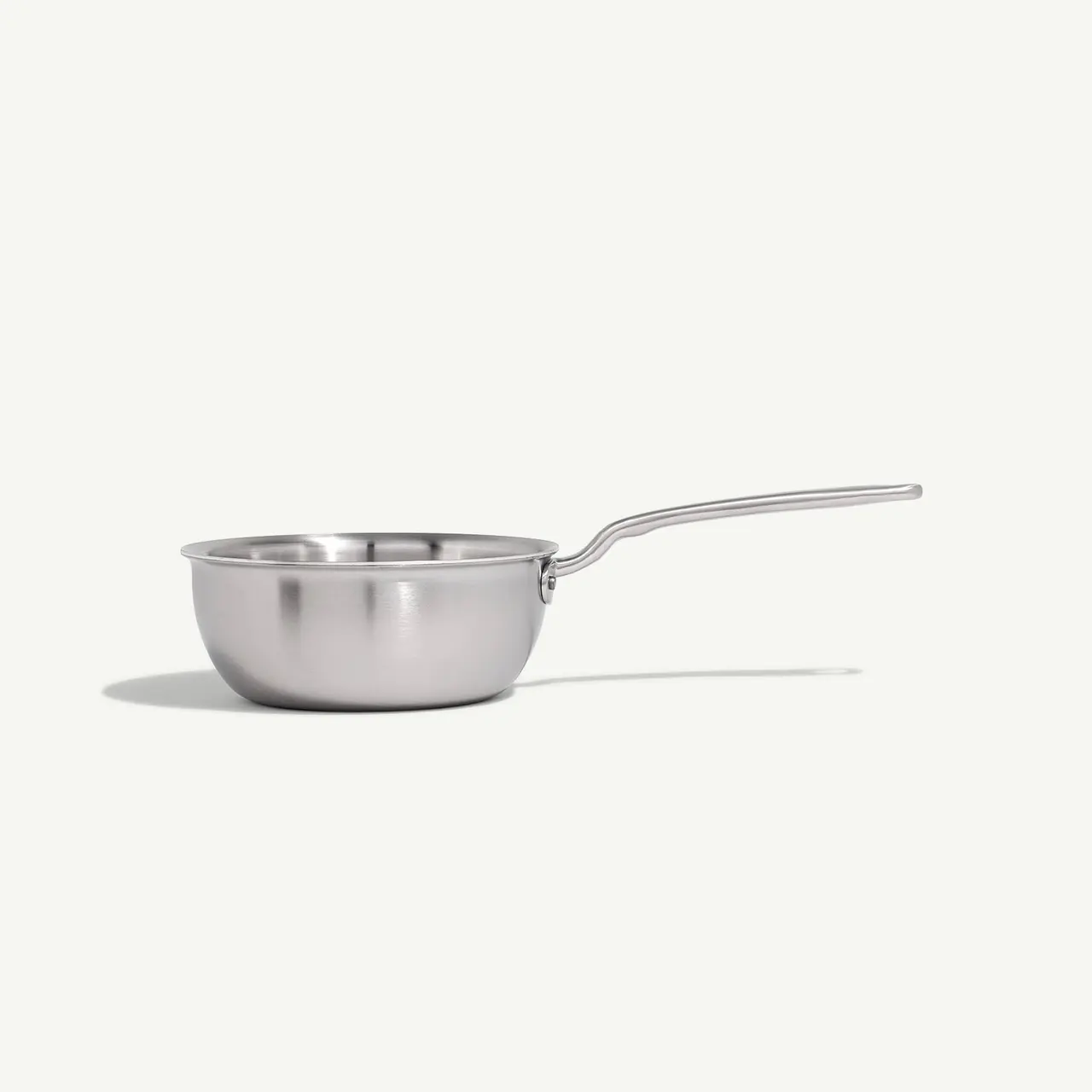A stainless steel saucepan with a long handle on a plain background.