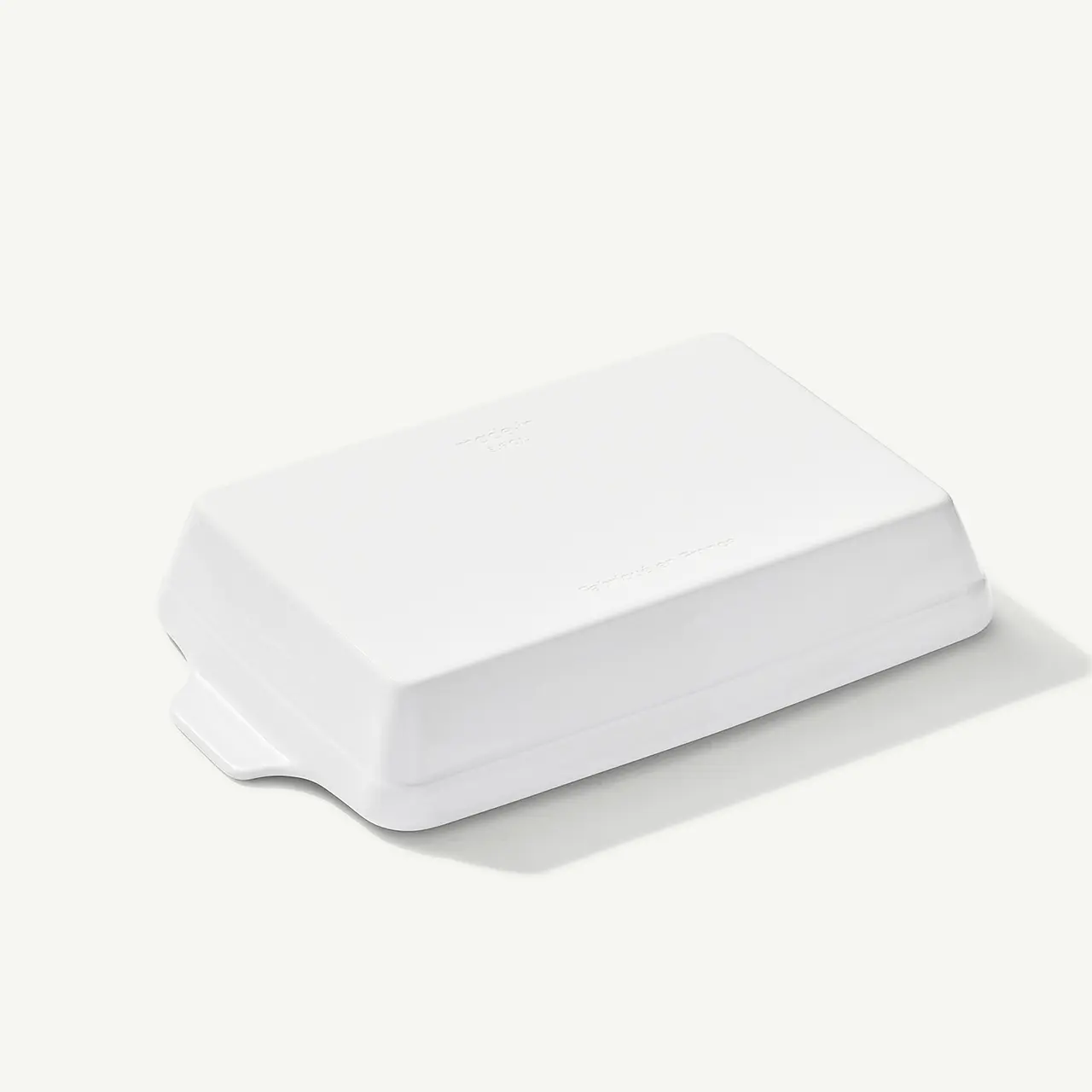A white rectangular electronic device with a minimalist design sits on a light background.