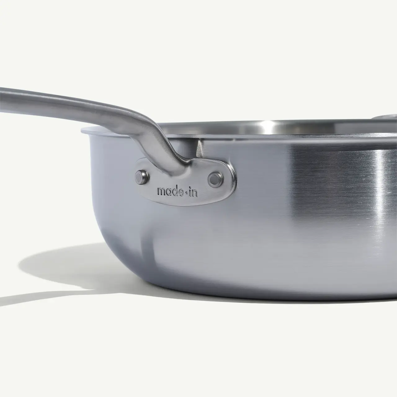 A close-up side view of a stainless steel saucepan with the brand name 'made in' visible on the handle.