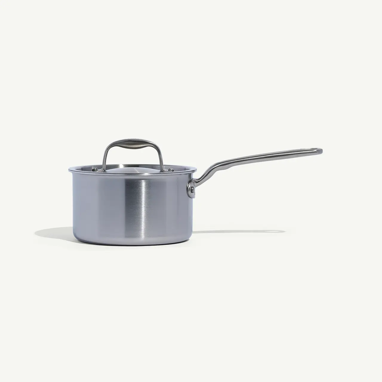 A stainless steel saucepan with a long handle is positioned on a plain background.