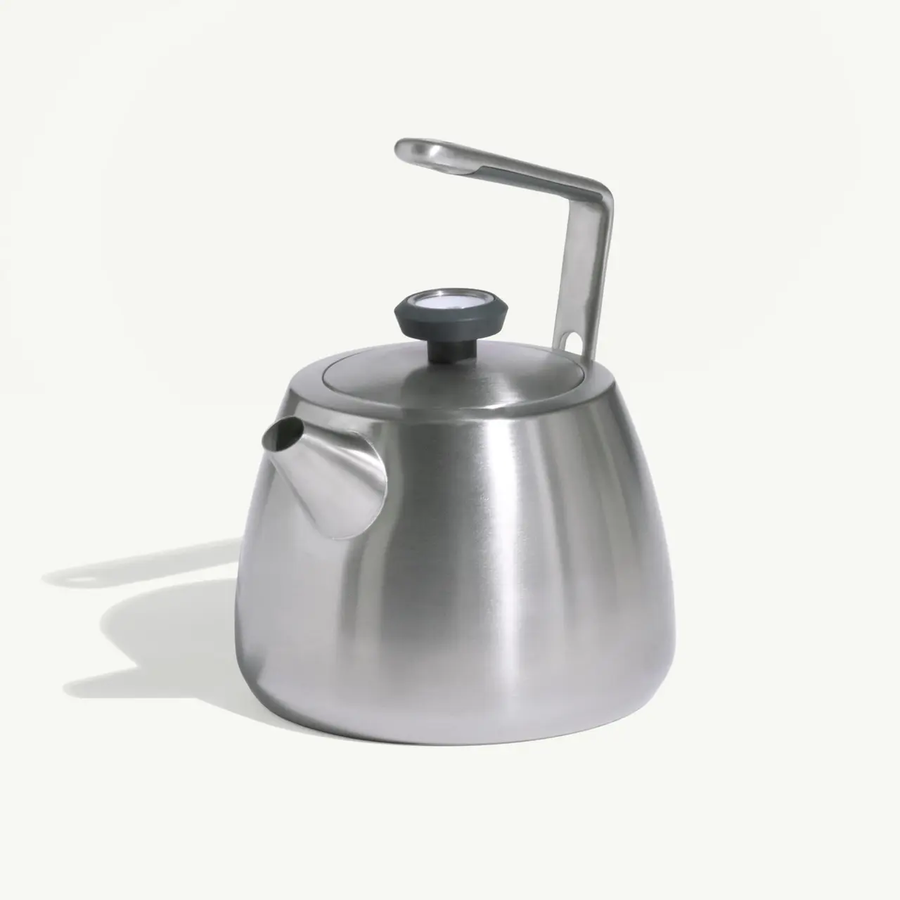 A sleek, silver stainless steel kettle with a curved body and a black handle is set against a light background.