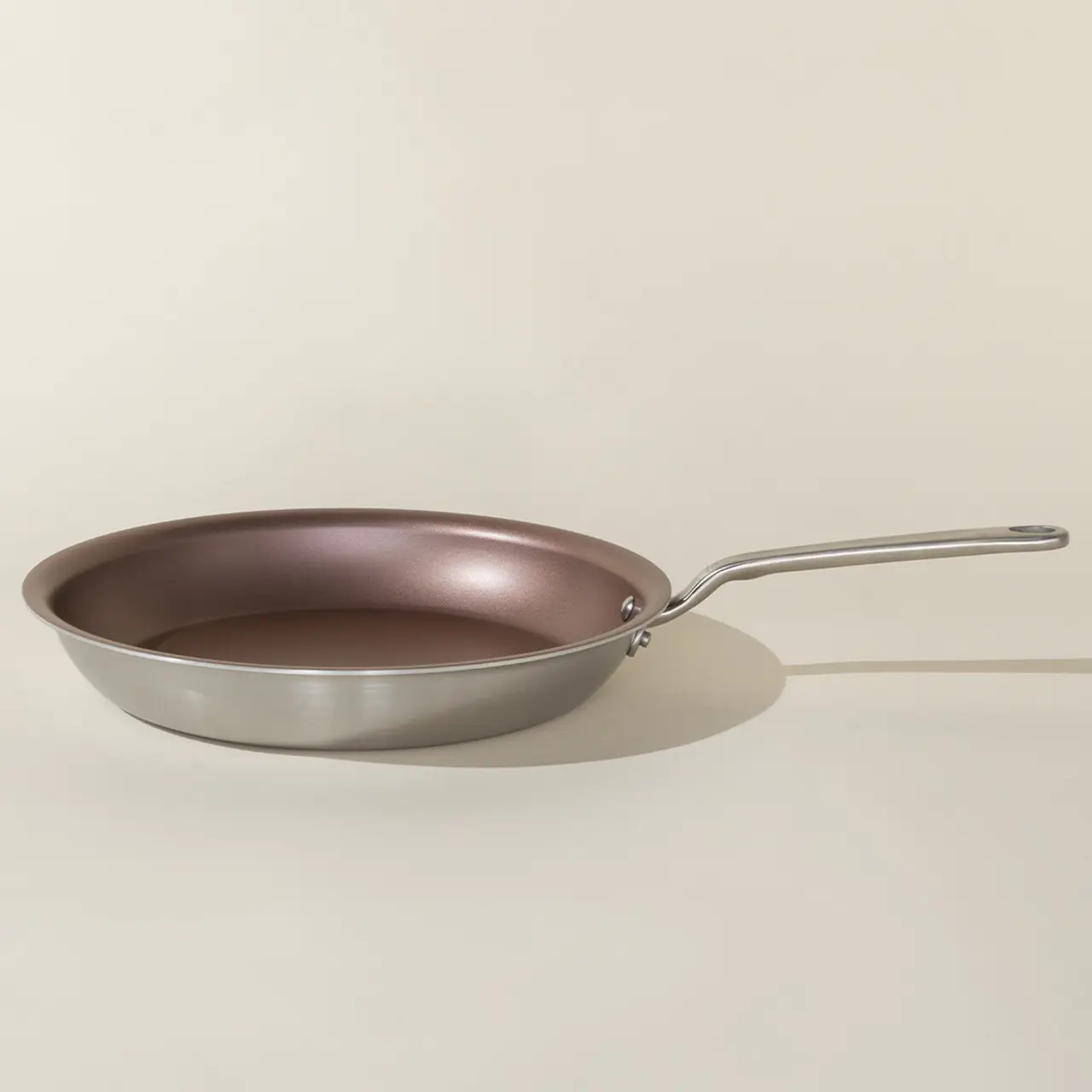 A non-stick frying pan with a stainless steel handle sits against a neutral background.
