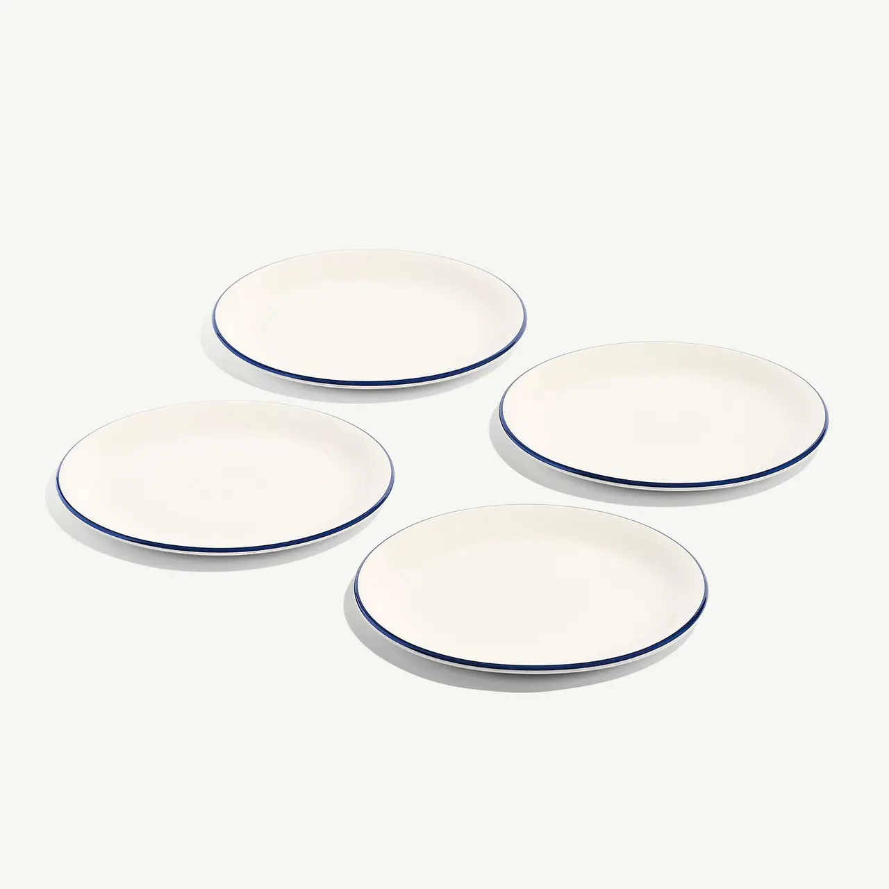 Four white plates with blue rims are neatly arranged on a light background.