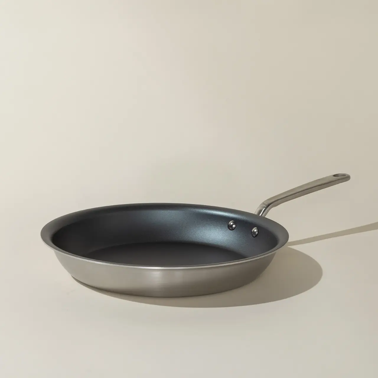 A non-stick frying pan with a silver handle is positioned against a neutral background.