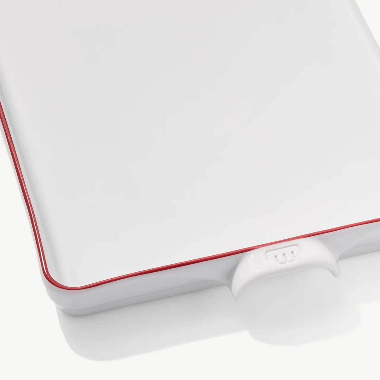 A closed white laptop with a red trim and a visible charging port.