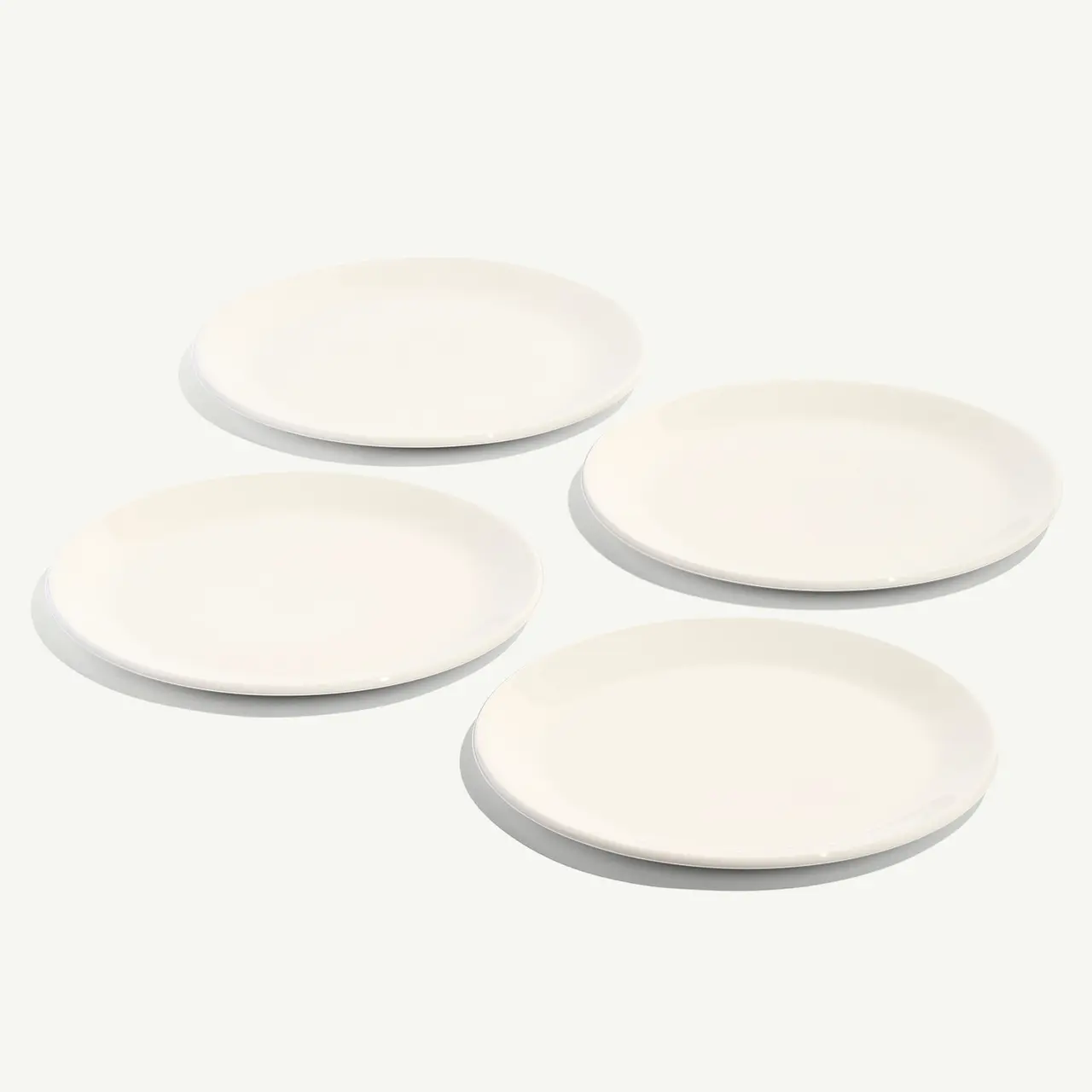 Four white plain plates are arranged on a light background.