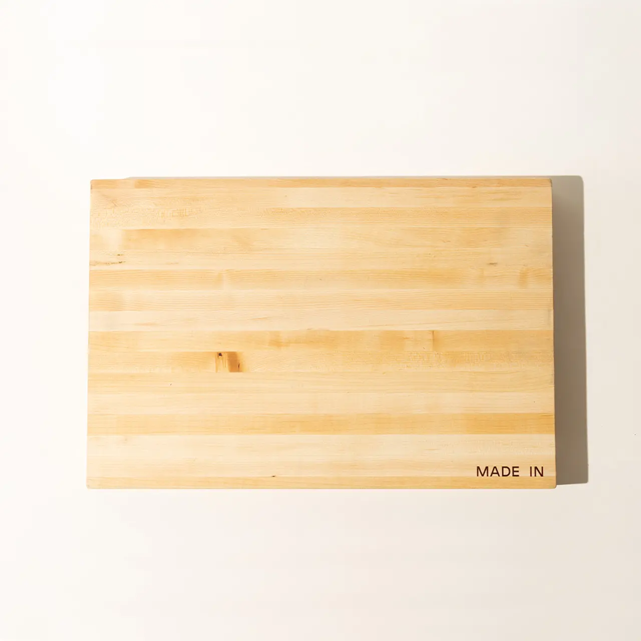 A rectangular bamboo cutting board with the text "MADE IN" stamped in the lower right corner, on a white background.