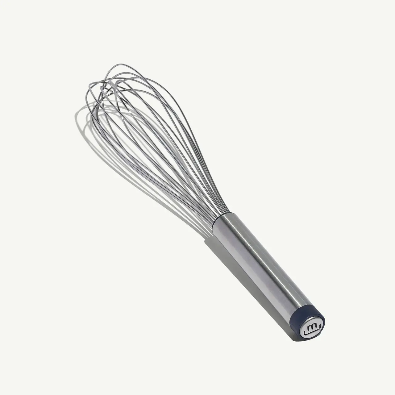 A metal whisk with a cylindrical handle lies against a plain background.