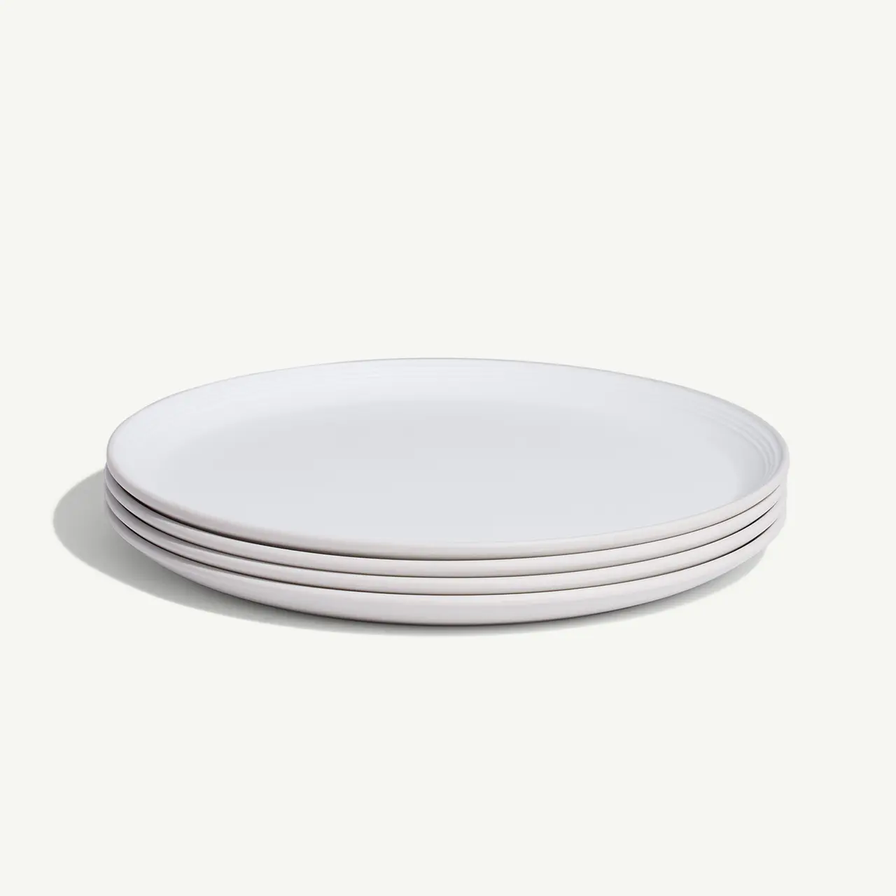 A stack of clean white plates is arranged on a light background.