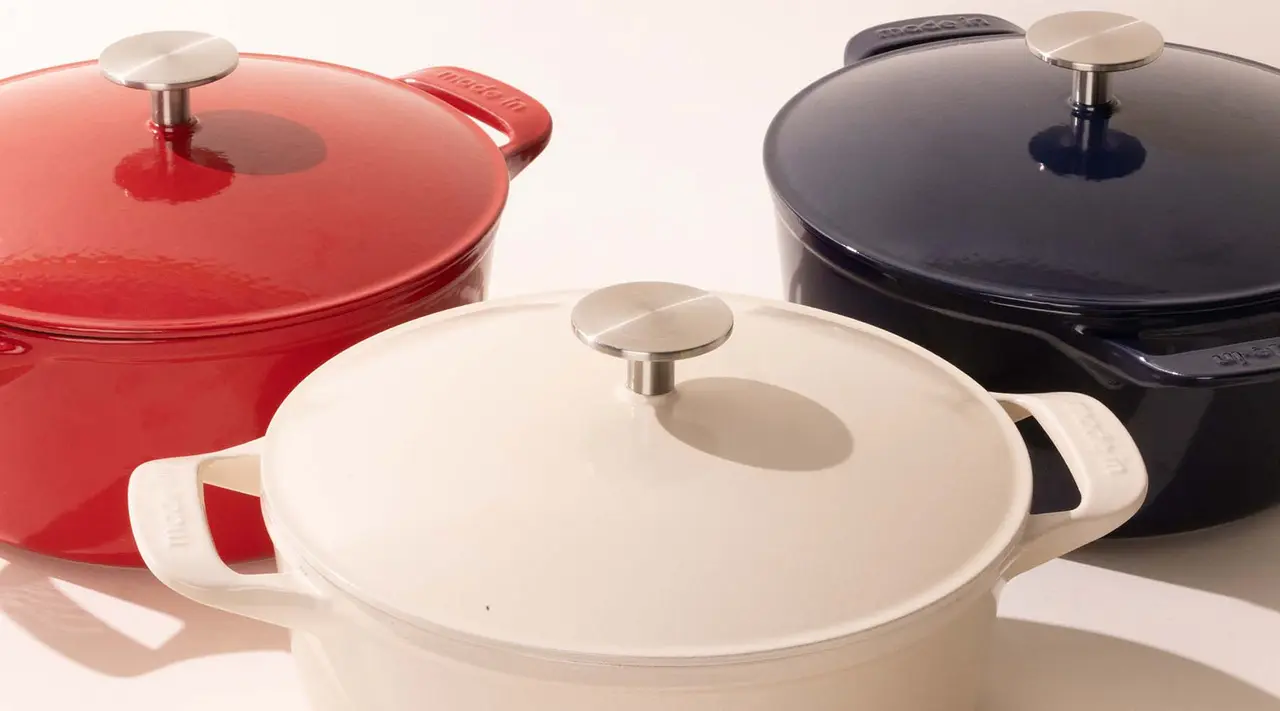 Three colorful enameled cast iron Dutch ovens with lids, in red, white, and blue, arranged diagonally.