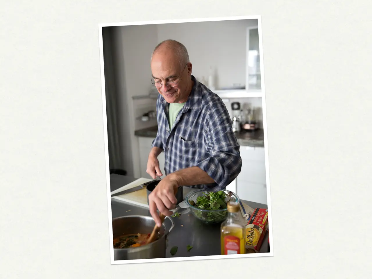 A smiling man is chopping vegetables in a modern kitchen.