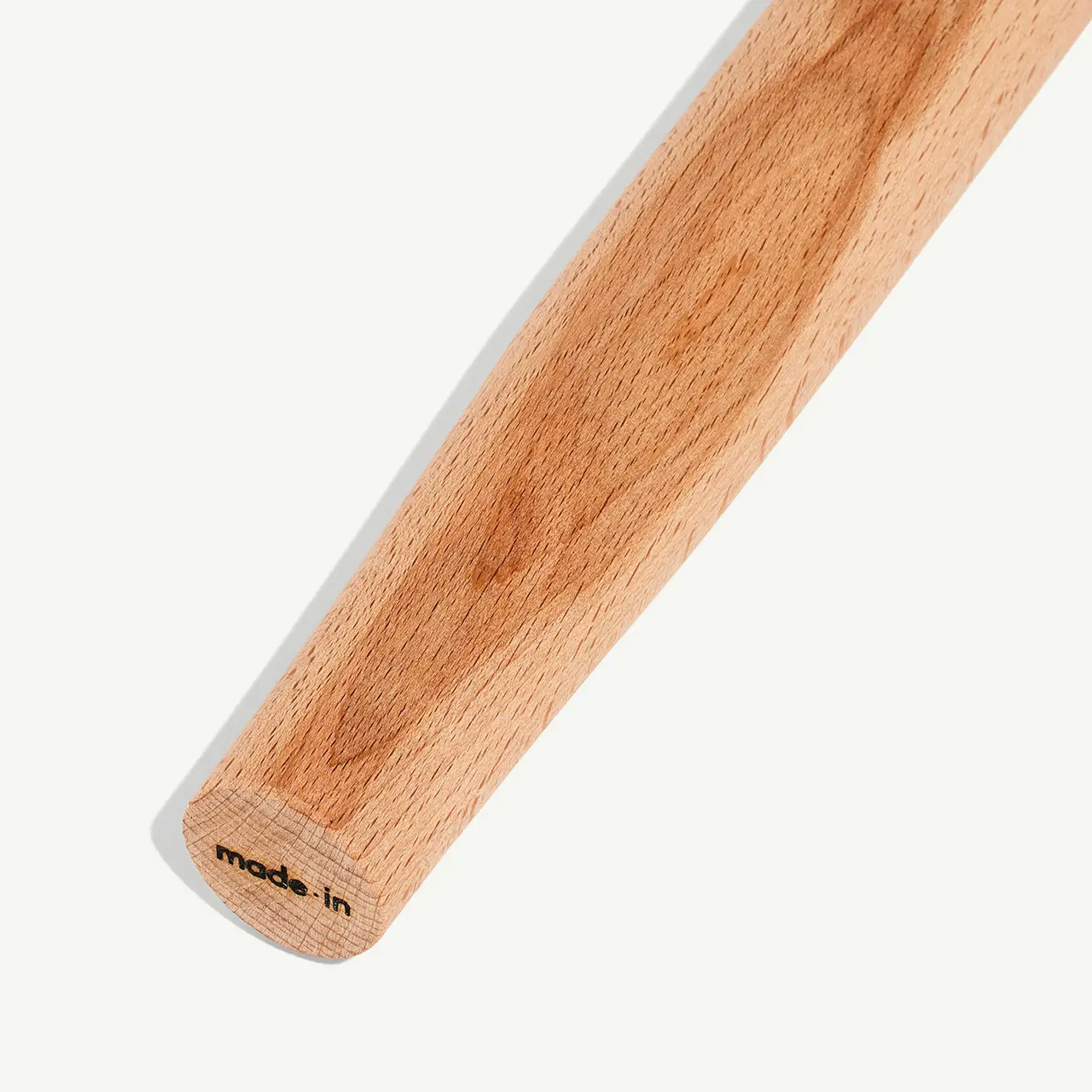 A close-up view of a wooden rolling pin with visible grain texture and a "made in" label on the handle.