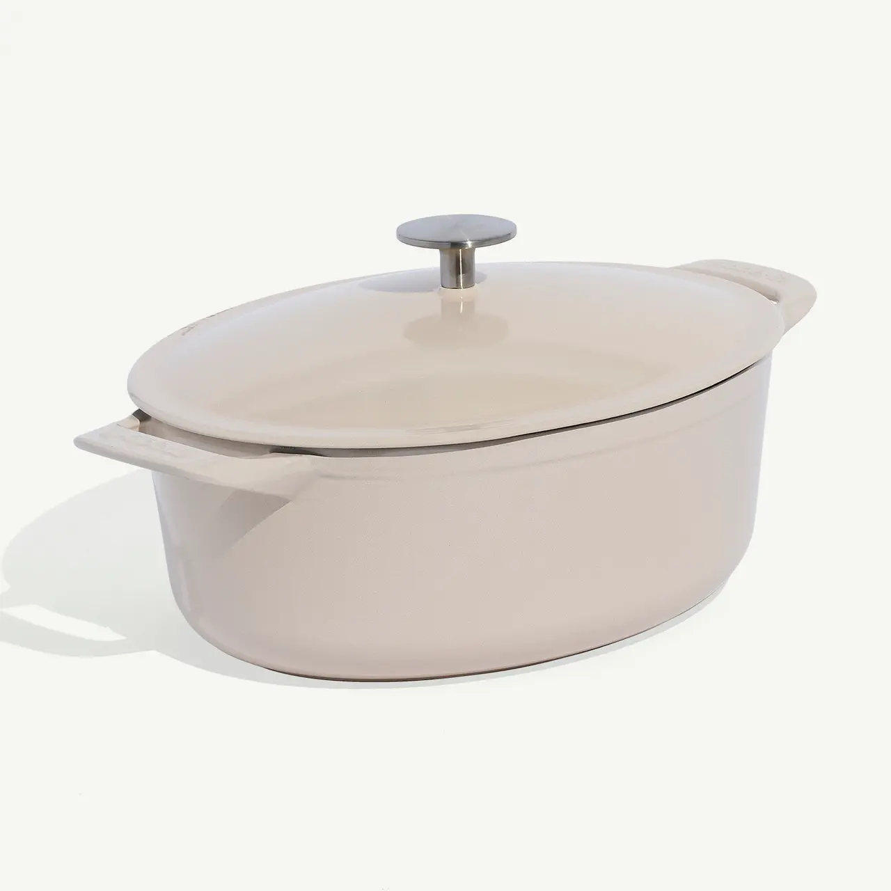 A beige oval Dutch oven with a lid sits against a white background.