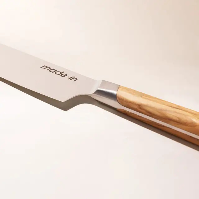 A close-up of a chef's knife with "made.in" printed on the blade and a wooden handle.
