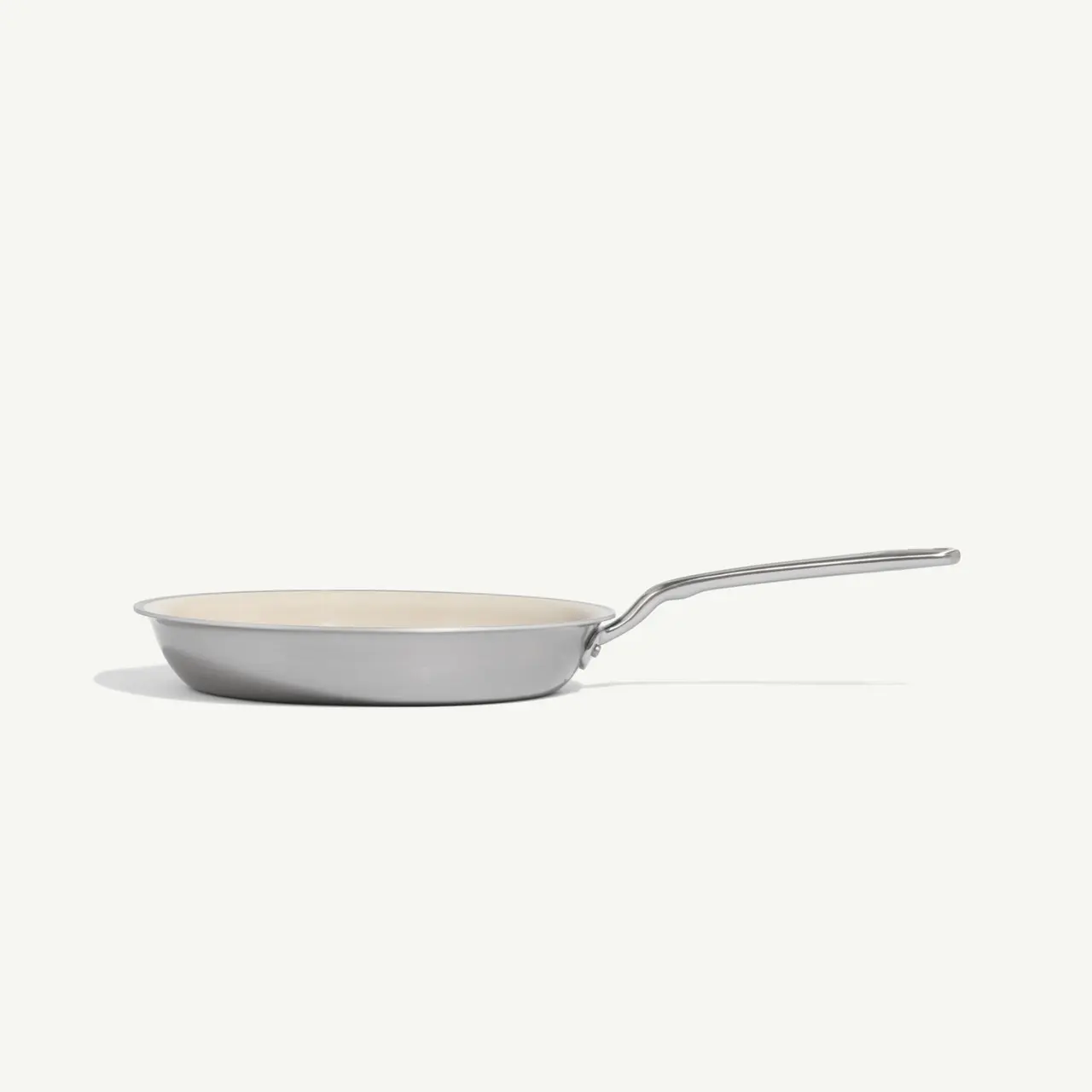 A gray frying pan with a long handle and a smooth interior surface rests on a light background.