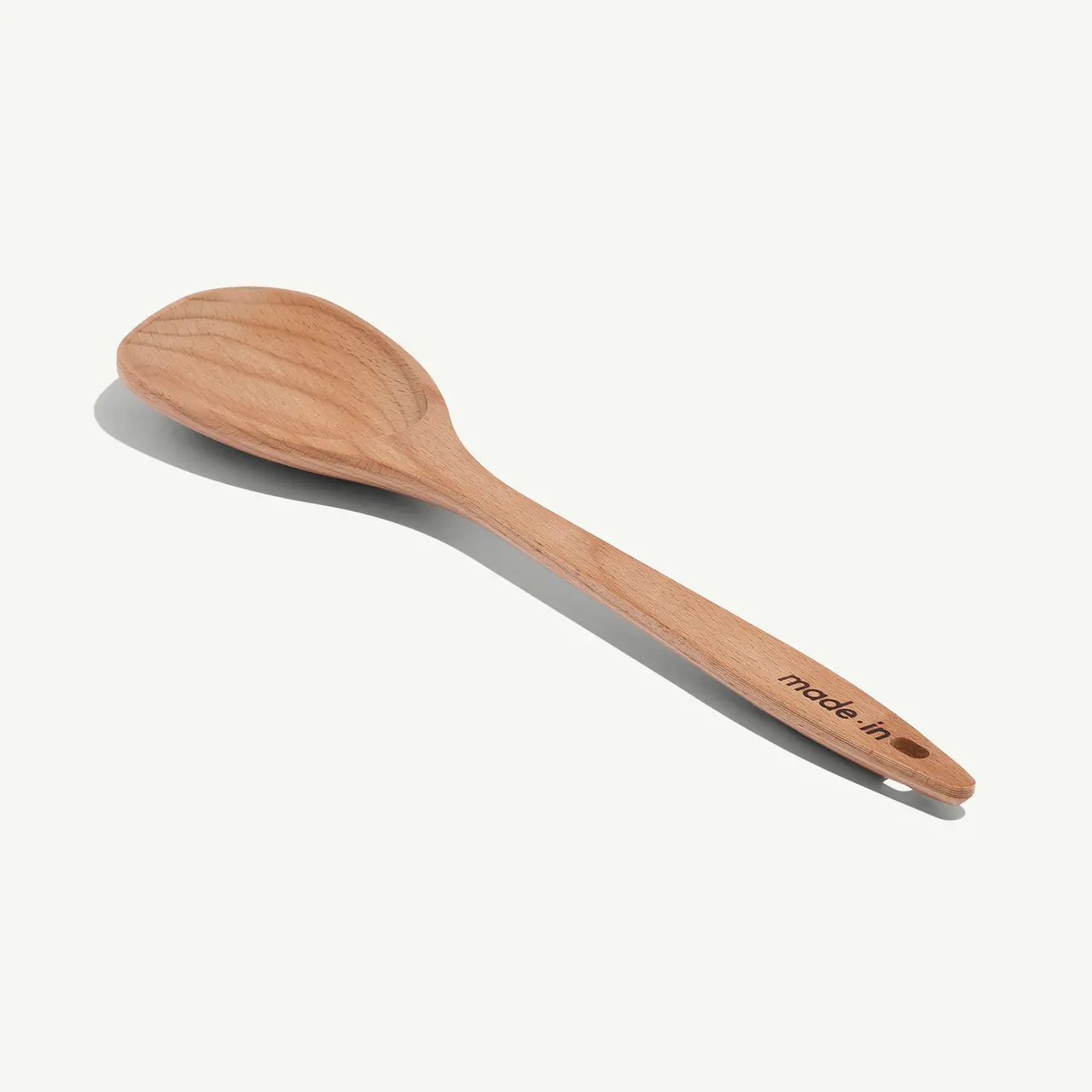 A simple wooden spoon rests on a white background.
