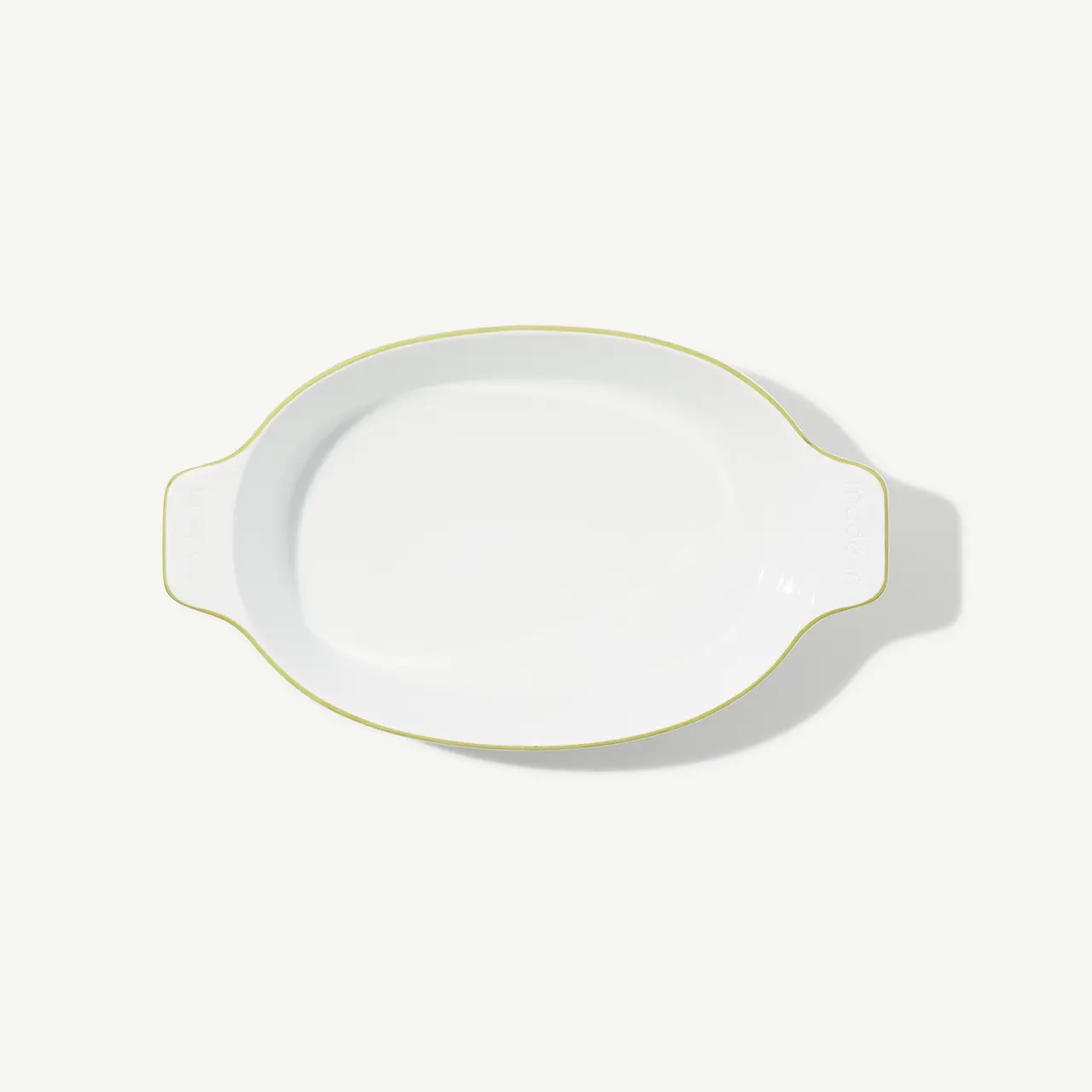 An oval-shaped white ceramic platter with a yellow rim on a plain background.