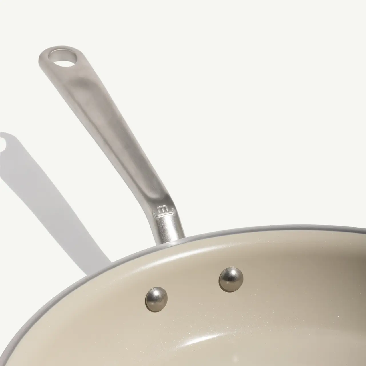 A non-stick frying pan with a stainless steel handle sits on a neutral background.