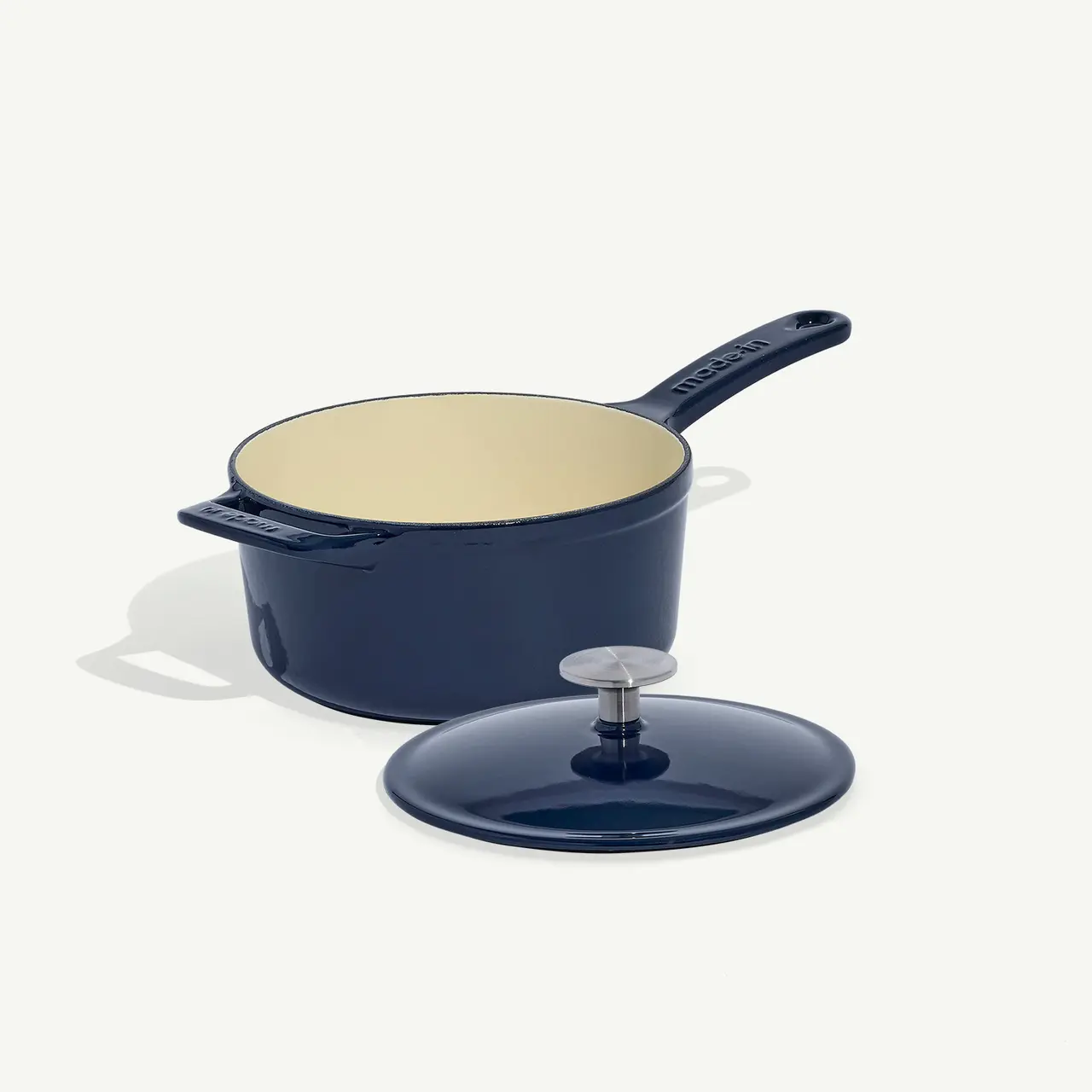 A navy blue saucepan with a matching lid placed beside it on a light background.