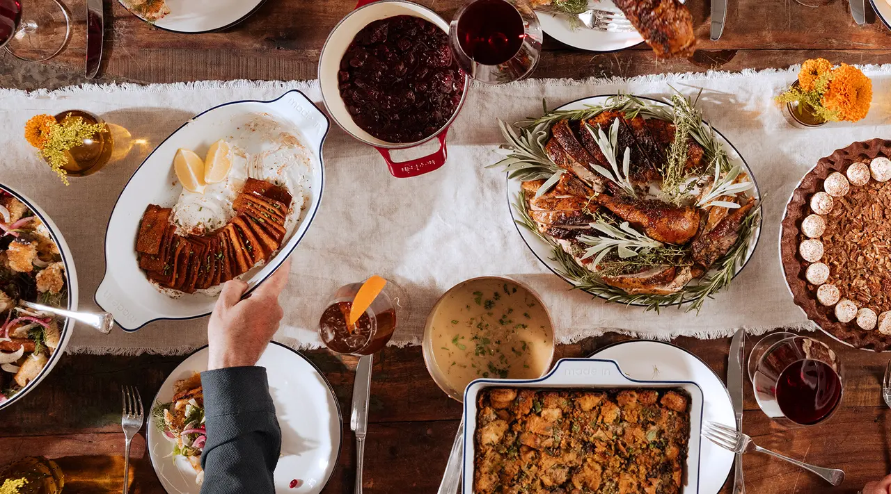 A festive table set with a variety of dishes, including a whole roasted turkey, sides, and sauces, indicative of a traditional Thanksgiving meal.