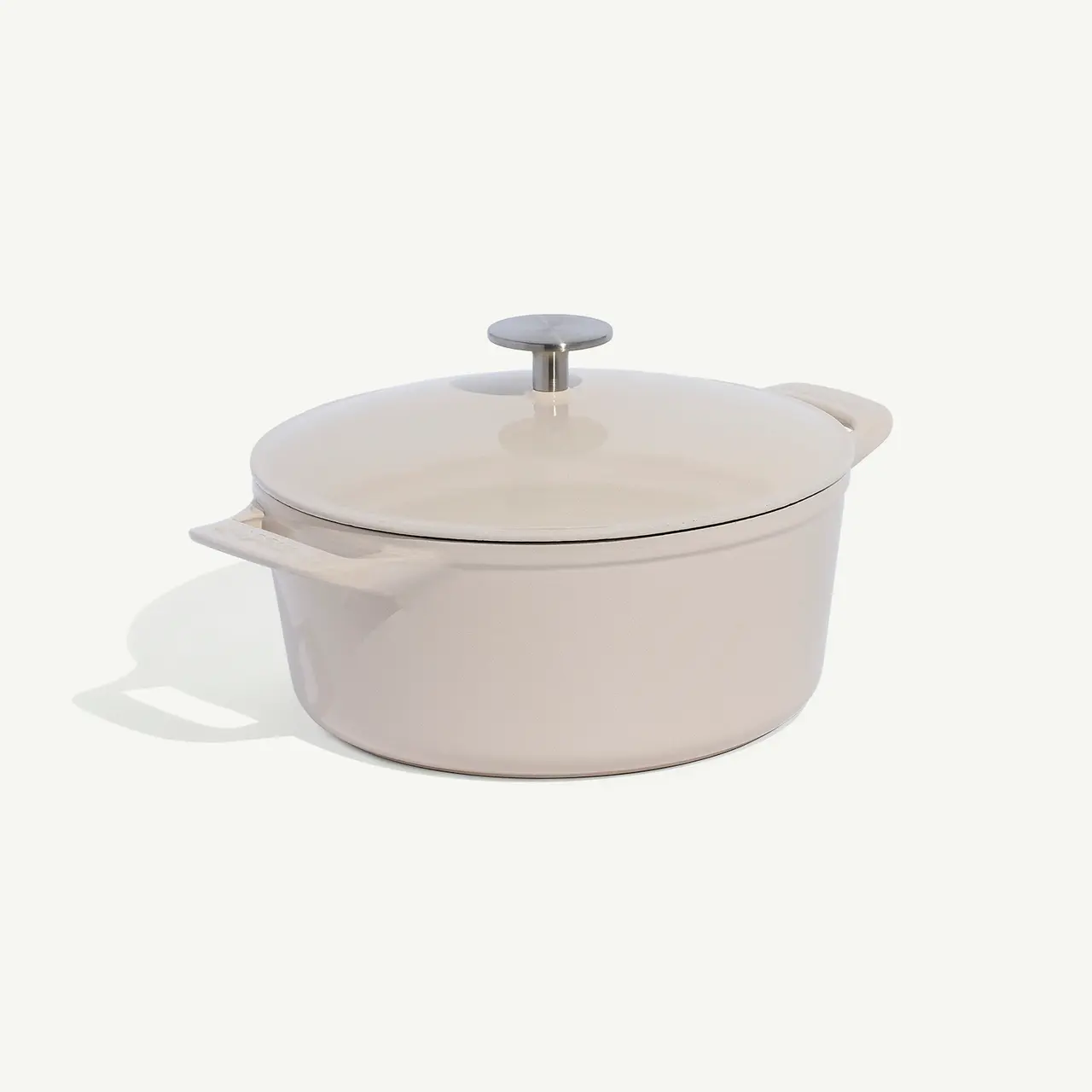 A white dutch oven pot with a lid on a plain background.