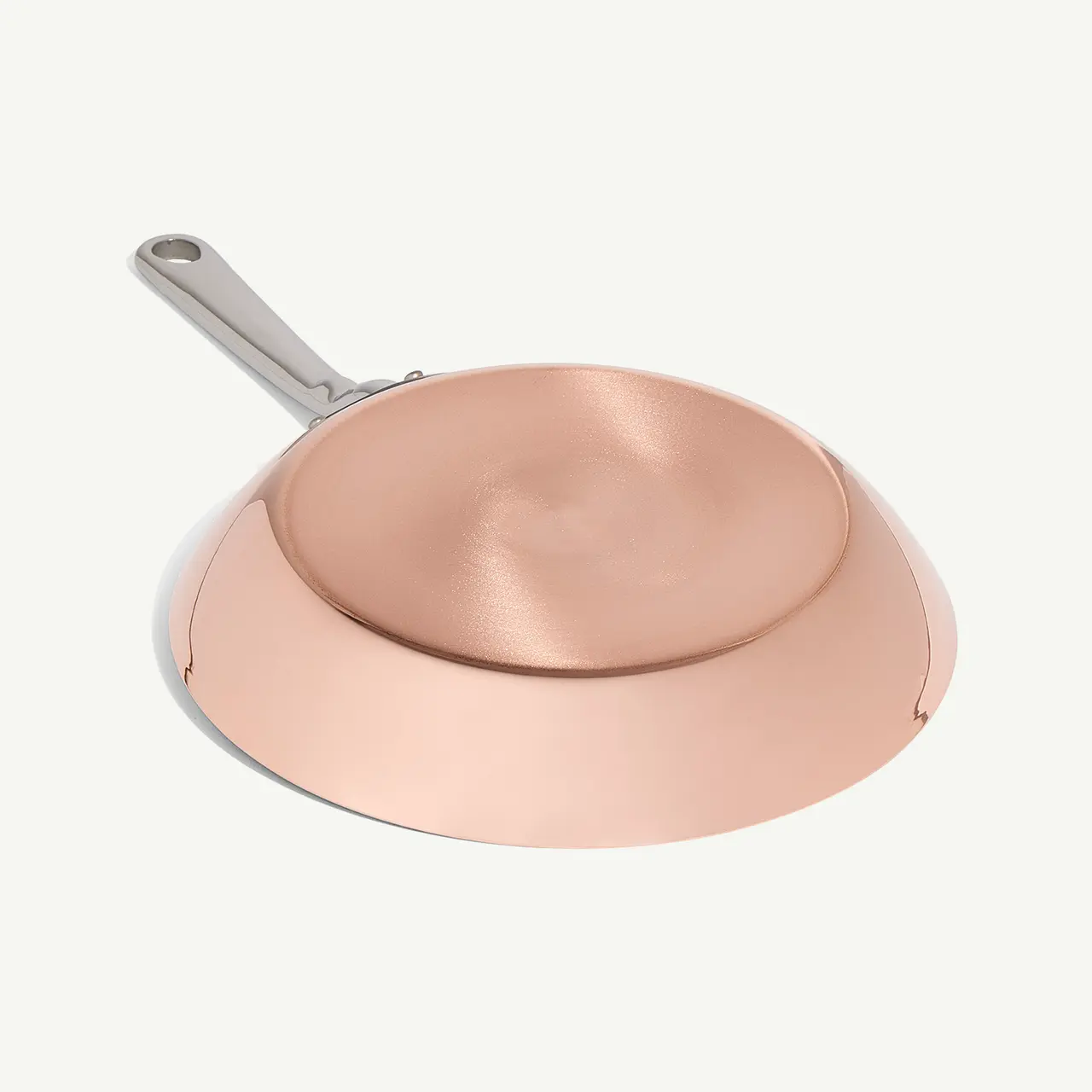 A copper-colored frying pan with a stainless steel handle is featured against a light background.