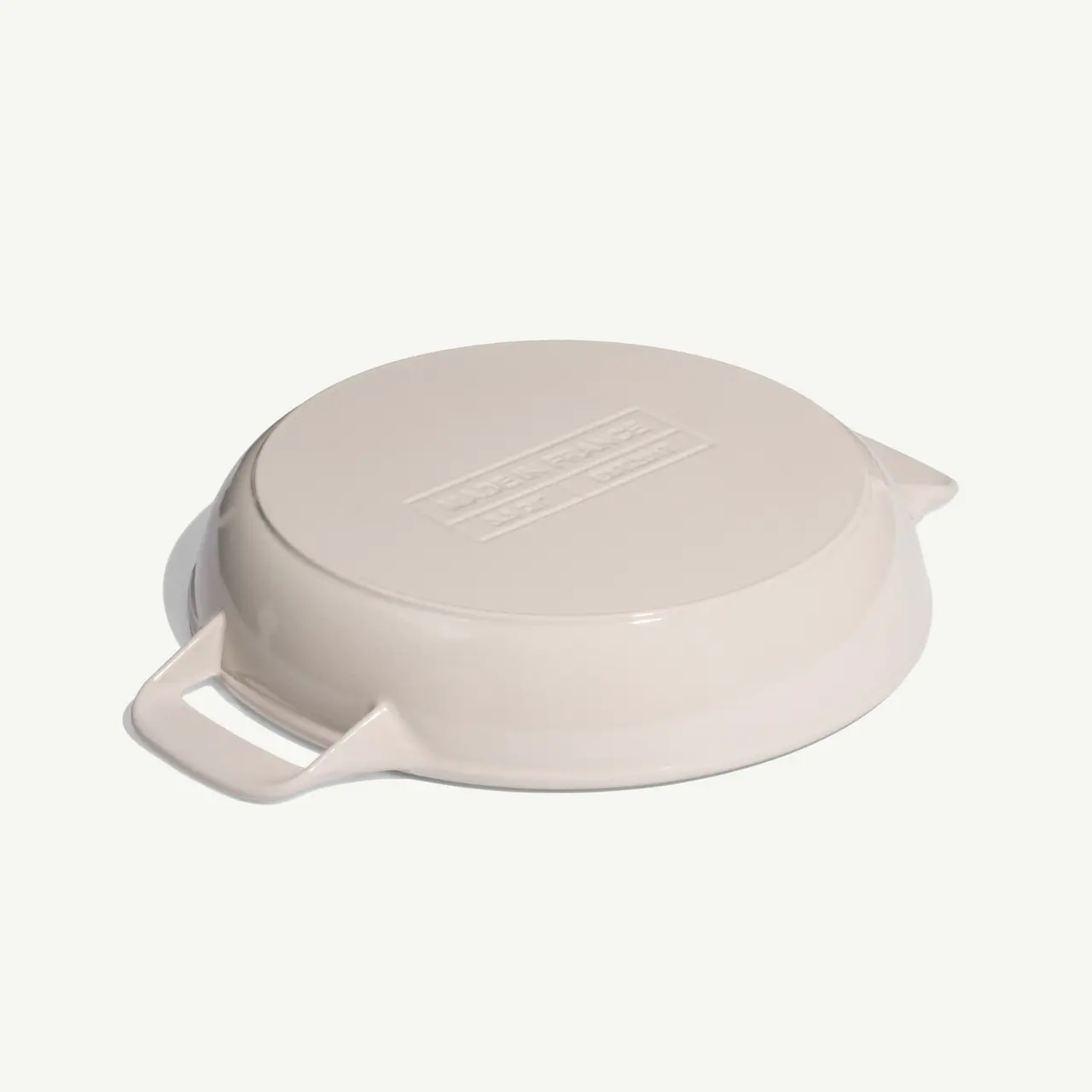A round, pale-colored lid with two side handles and a textured surface.