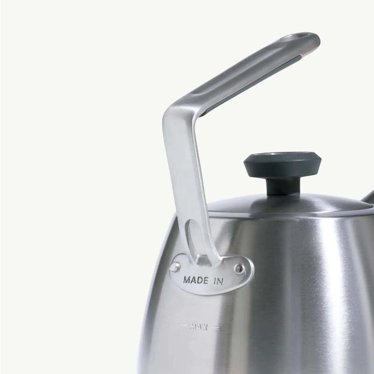 A sleek stainless steel kettle with a black handle and knob, featuring the inscription "MADE IN."