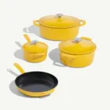 Bright yellow cookware set featuring three pots with lids and one frying pan.