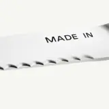 A close-up of a metallic blade showing the phrase "MADE IN" etched onto its surface.