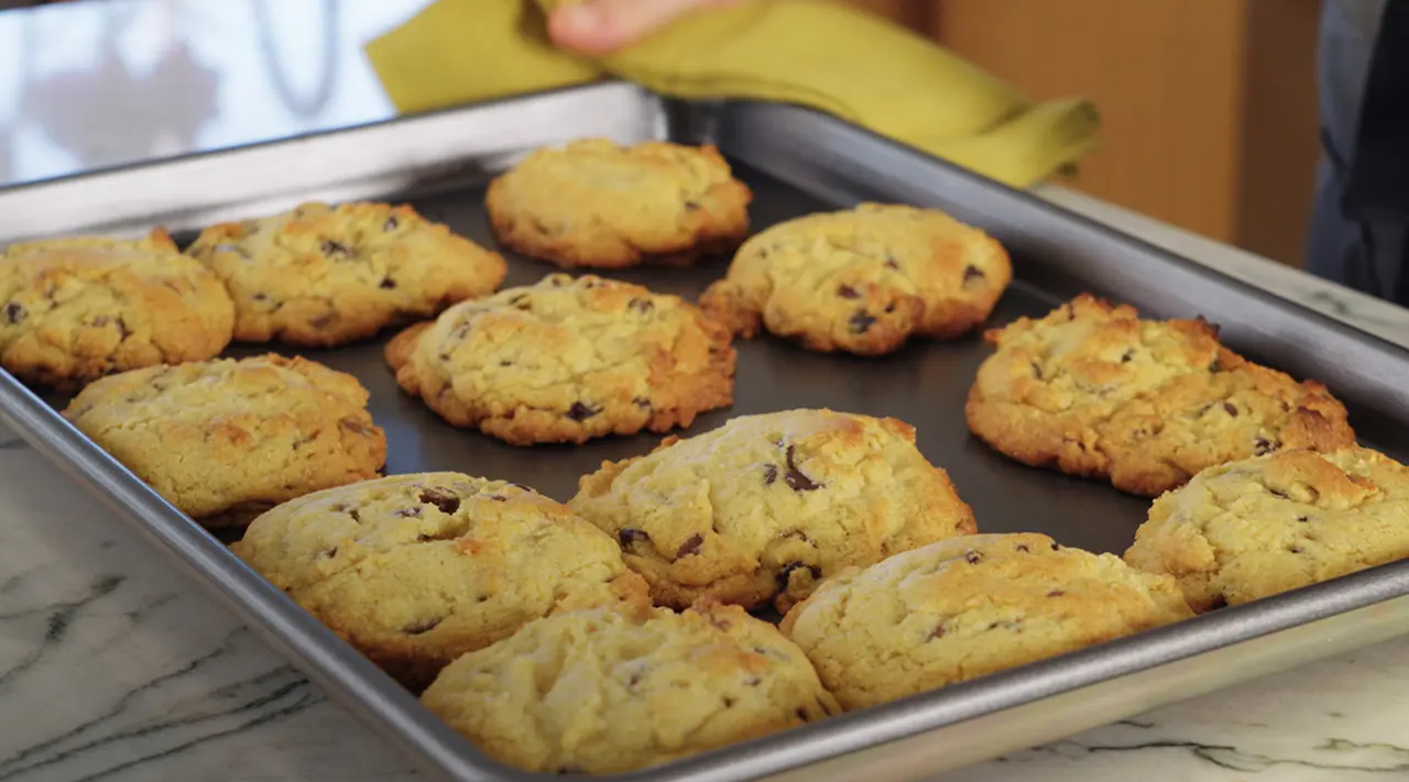 A tray with freshly baked cookies is placed on a marble countertop.