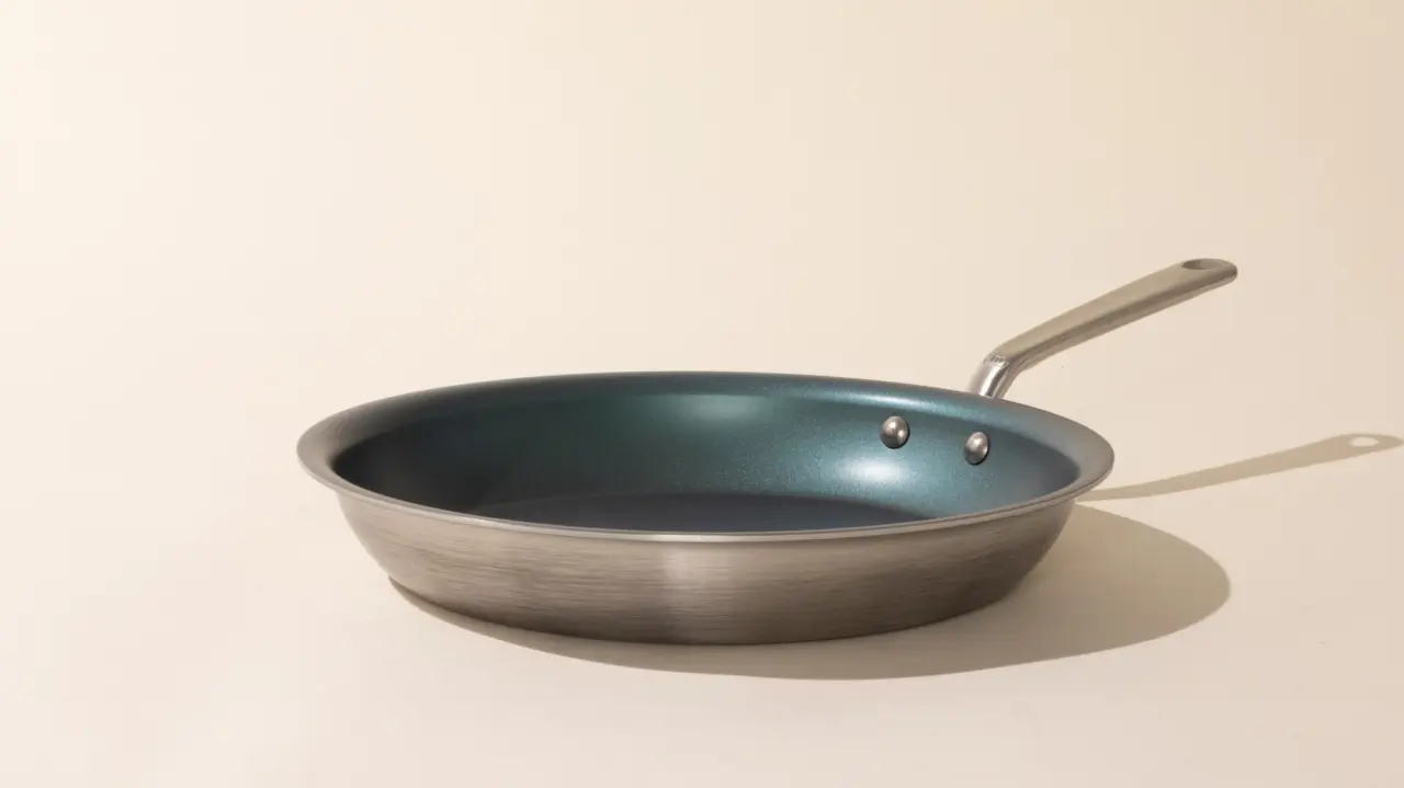 A single non-stick frying pan with a stainless steel handle on a neutral background, casting a slight shadow.